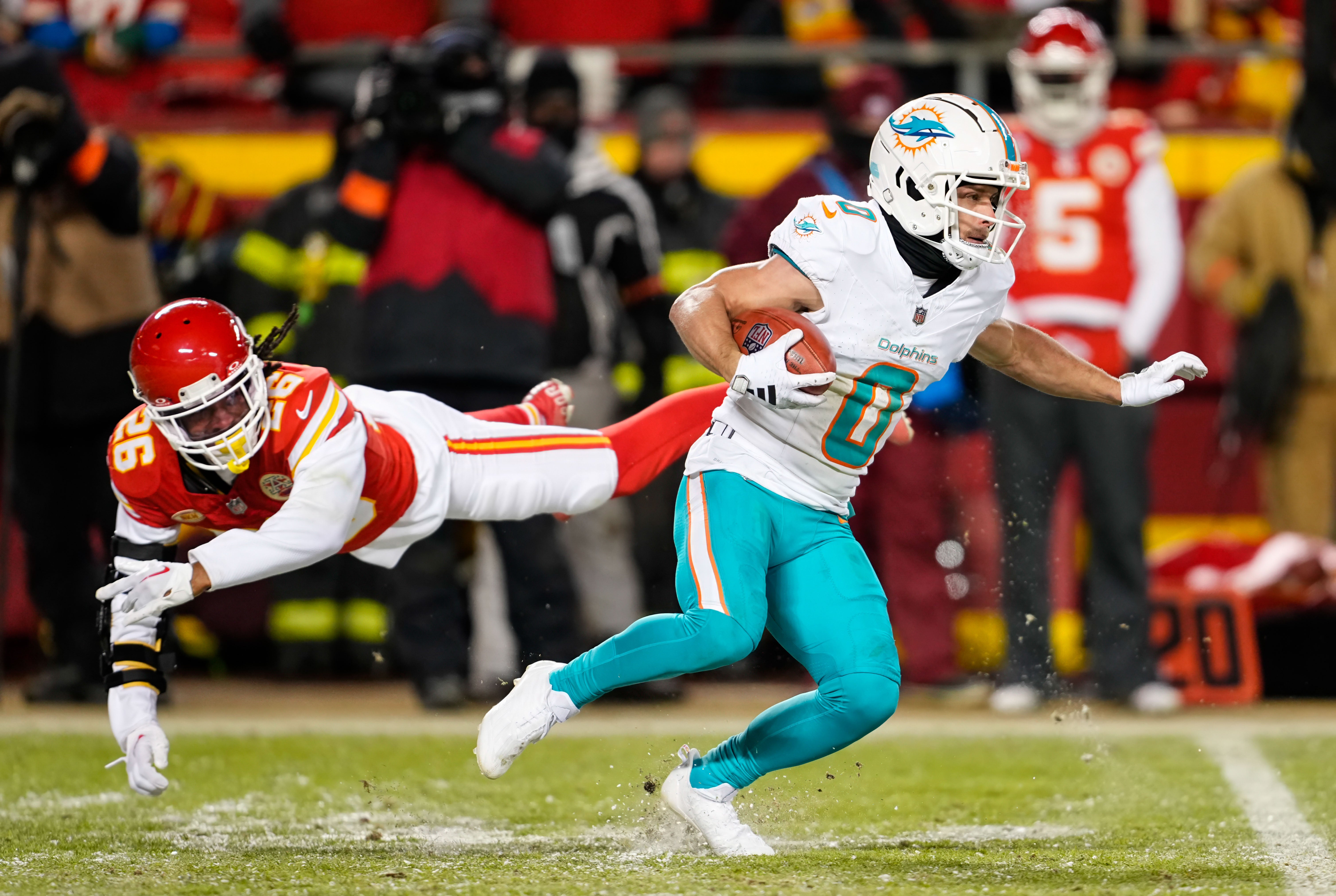 Jan 13, 2024; Kansas City, Missouri, USA; Miami Dolphins wide receiver Braxton Berrios (0) returns a kickoff against Kansas City Chiefs safety Deon Bush (26) during the second half of a 2024 AFC wild card game at GEHA Field at Arrowhead Stadium.