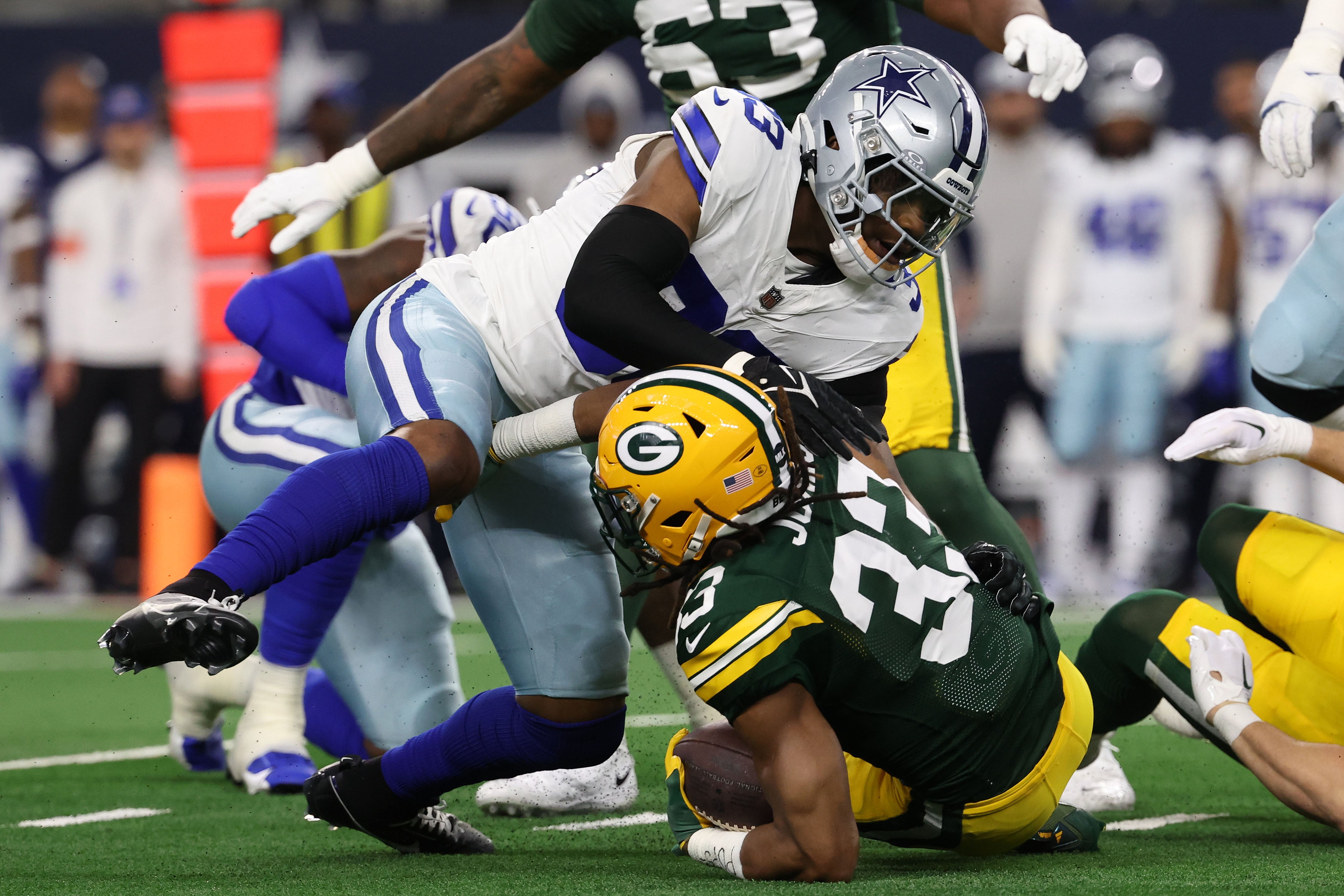 Dallas Cowboys linebacker Damone Clark (33) tackles Green Bay Packers running back Aaron Jones (33) during the first quarter for the 2024 NFC wild card game at AT&T Stadium.