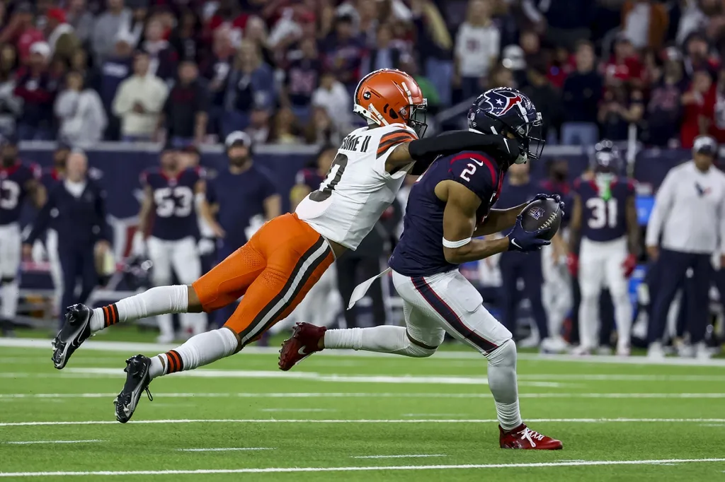 Cleveland Browns cornerback Greg Newsome II (0) tackled Houston Texans wide receiver Robert Woods (2) after an interception during the third quarter in a 2024 AFC wild card game at NRG Stadium.