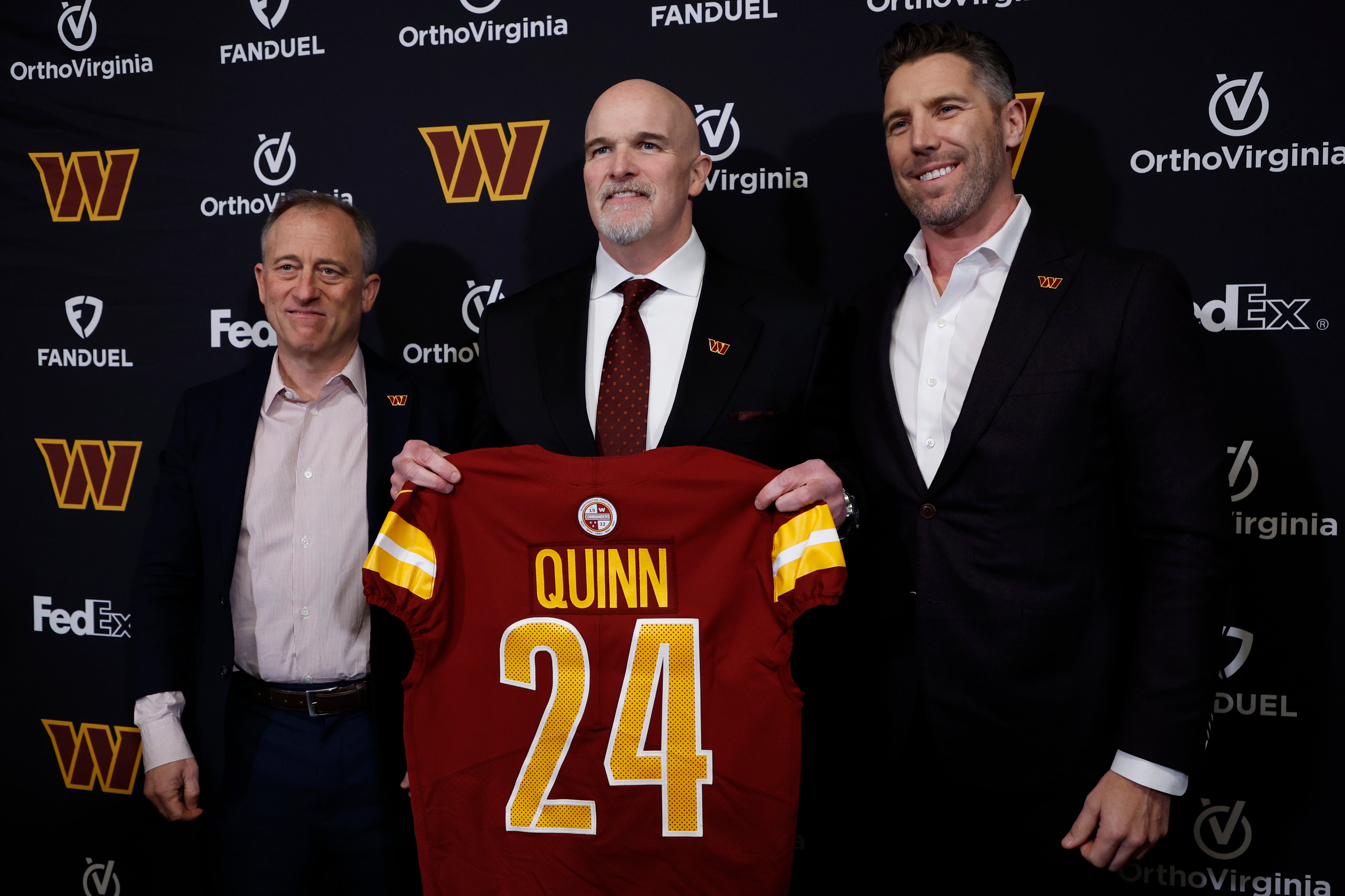 Washington Commanders head coach Dan Quinn (M) poses for a picture with Commanders managing partner Josh Harris (L) and Washington Commanders general manager Adam Peters (R) at an introductory press conference at Commanders Park.