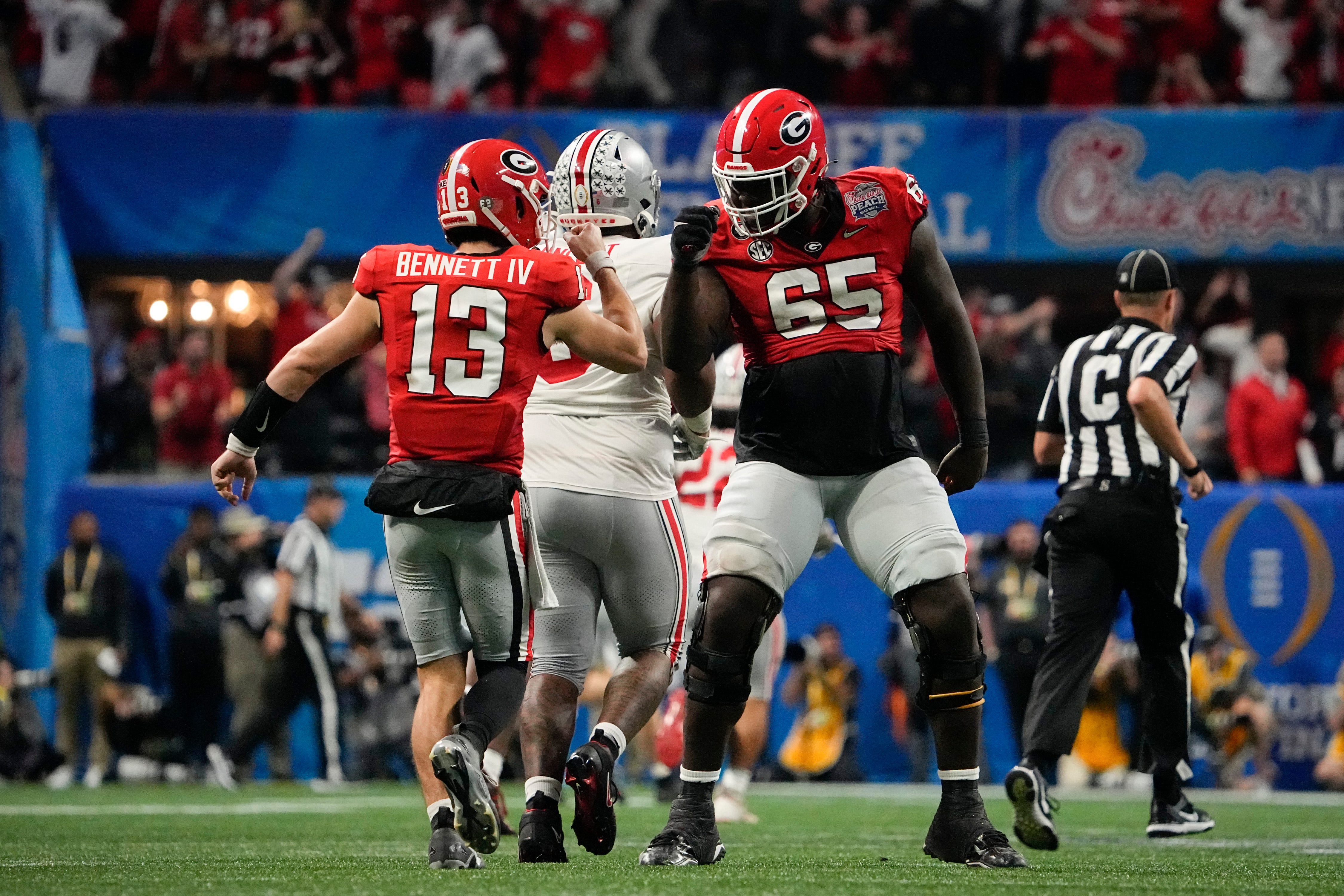 Dec 31, 2022; Atlanta, Georgia, USA; Georgia Bulldogs quarterback Stetson Bennett (13) gets a fist pump from offensive lineman Amarius Mims (65) after a touchdown pass during the second half of the Peach Bowl against the Ohio State Buckeyes in the College Football Playoff semifinal at Mercedes-Benz Stadium. Ohio State lost 42-41.