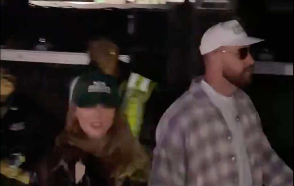 Taylor Swift wearing a New Heights hat while at Coachella with Travis Kelce.
