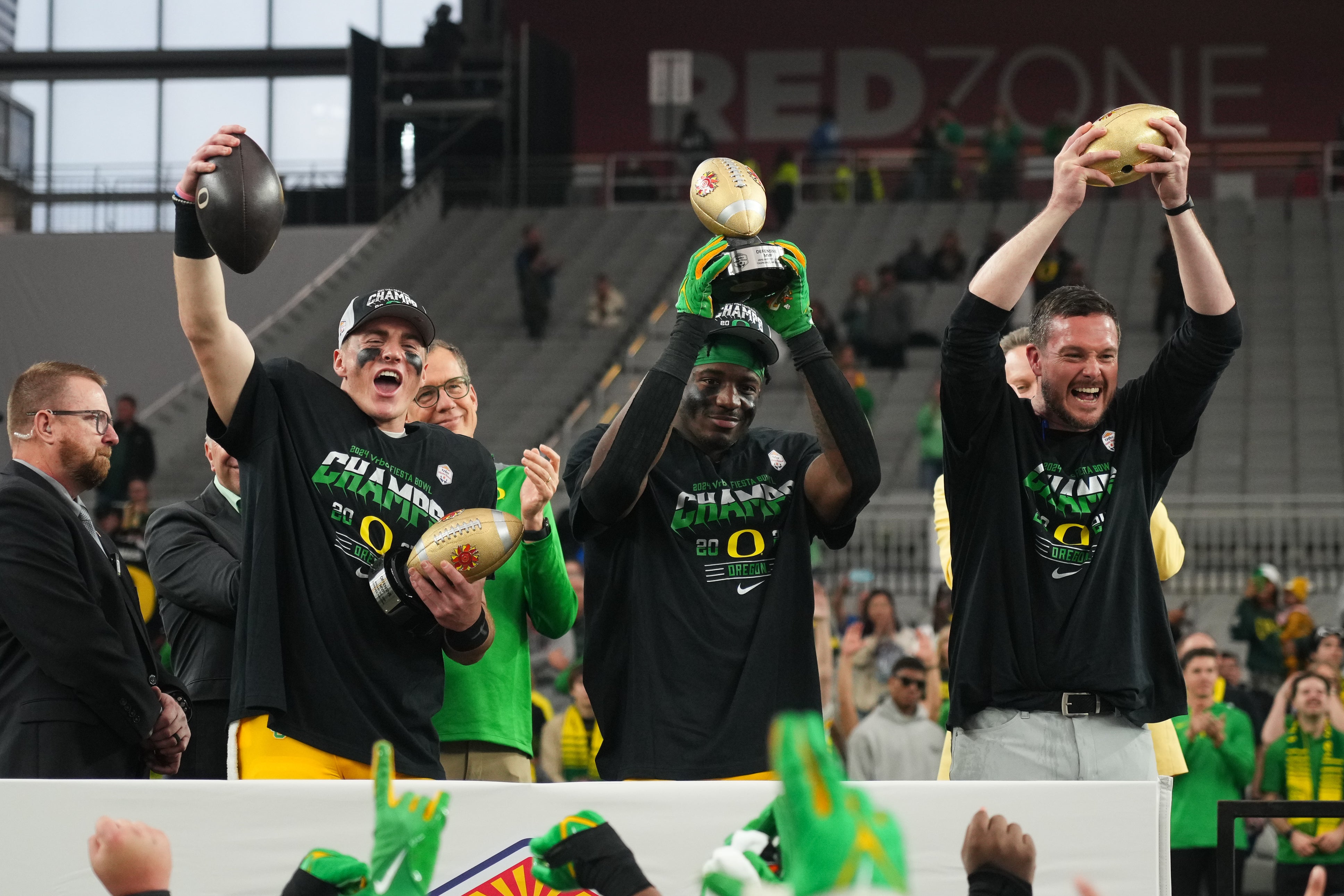 Jan 1, 2024; Glendale, AZ, USA; Oregon Ducks quarterback Bo Nix (10), linebacker Jeffrey Bassa (2) and head coach Dan Lanning lift the offensive MVP, defensive MVP and championship trophy after a victory in the 2024 Fiesta Bowl against the Liberty Flames at State Farm Stadium.