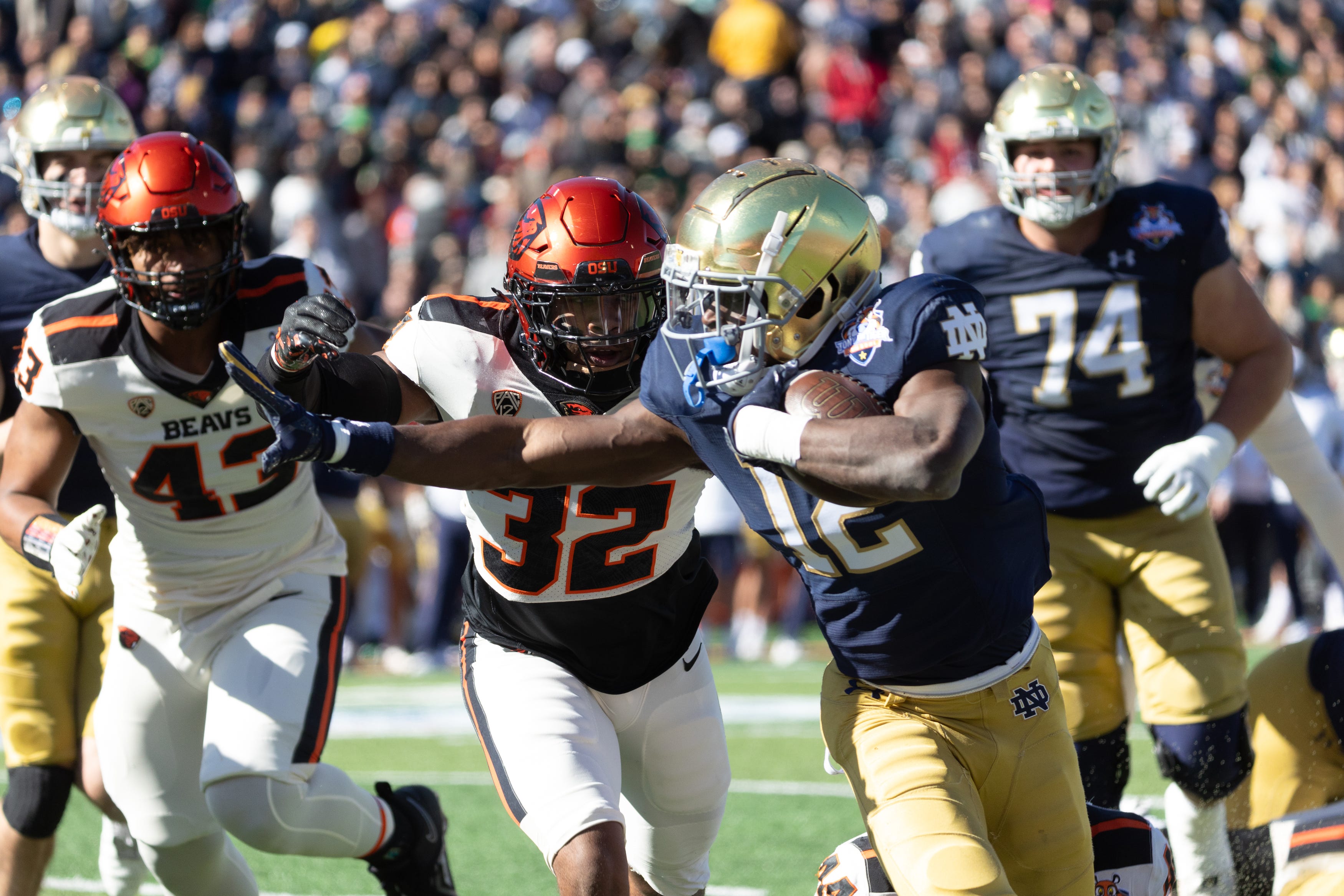 Notre Dame's Jeremiyah Love (12) stiff arms Oregon State players at the 90th Sun Bowl game in El Paso, Texas Friday, Dec. 29, 2023,