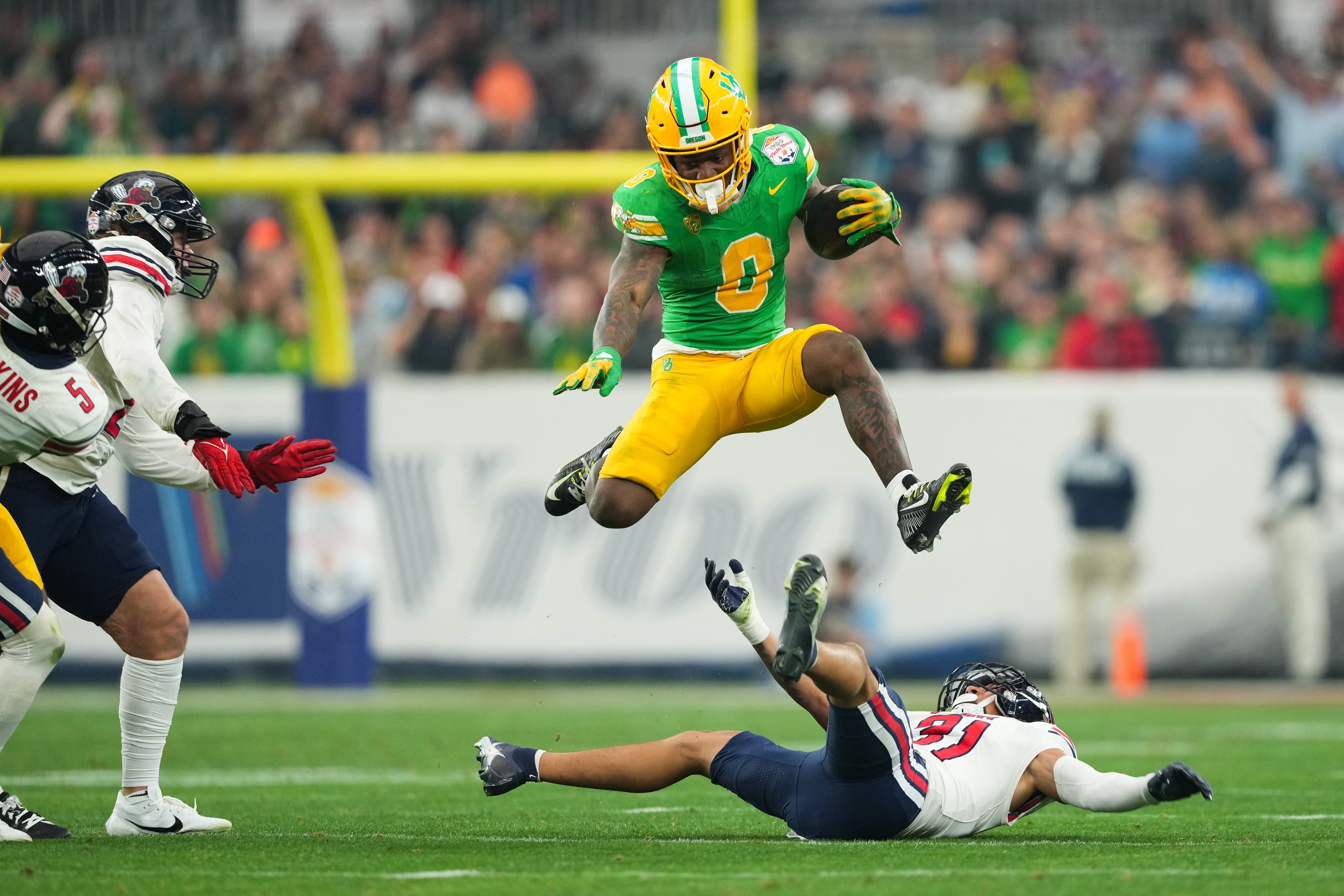 Oregon Ducks running back Bucky Irving (0) hurdles over Liberty Flames defensive back Brandon Bishop (6) during the second half in the 2024 Fiesta Bowl at State Farm Stadium.