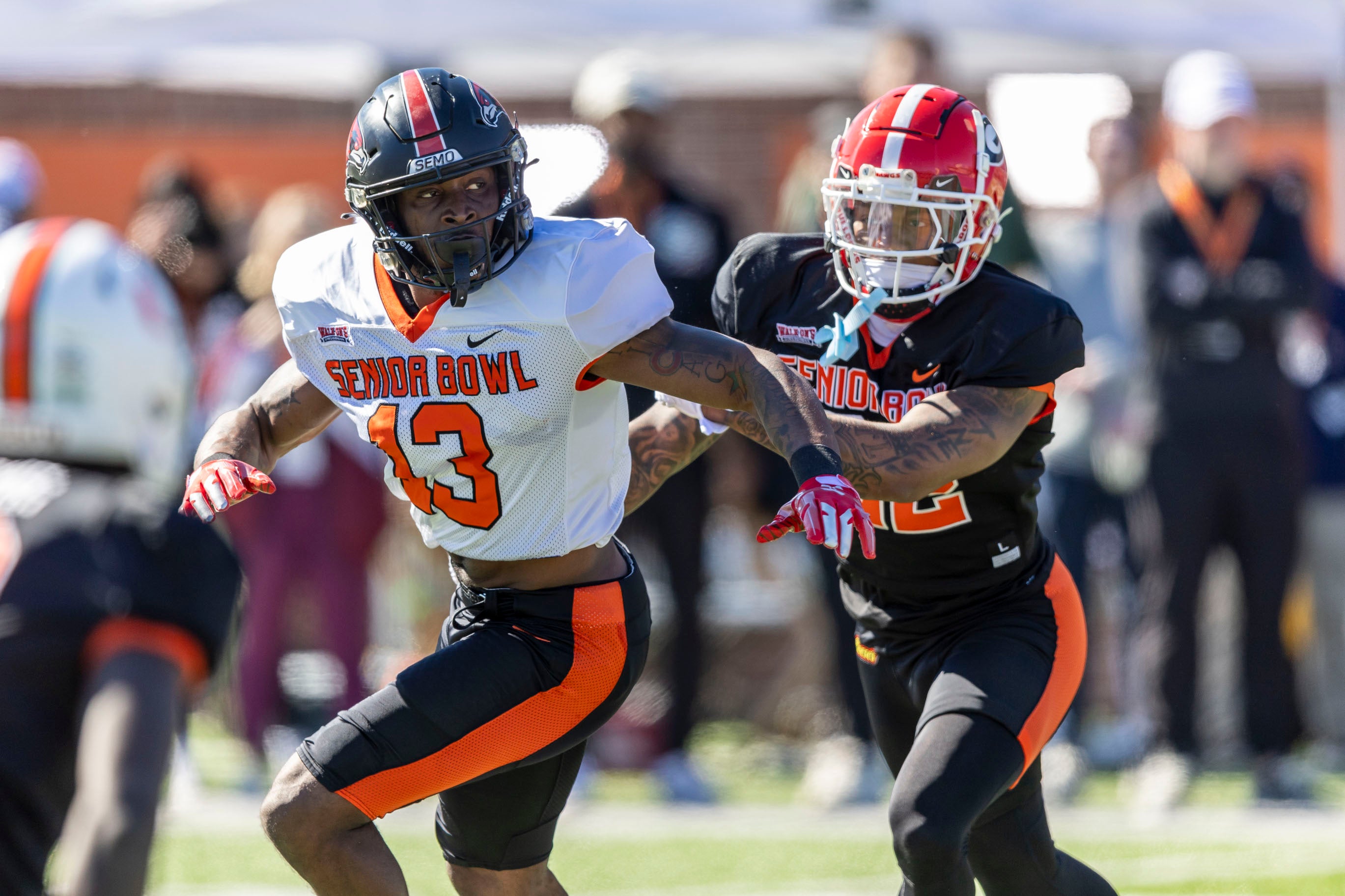 American wide receiver Ryan Flournoy of Southeast Missouri (13) runs past American defensive back Javon Bullard of Georgia (22) during practice for the American team at Hancock Whitney Stadium.