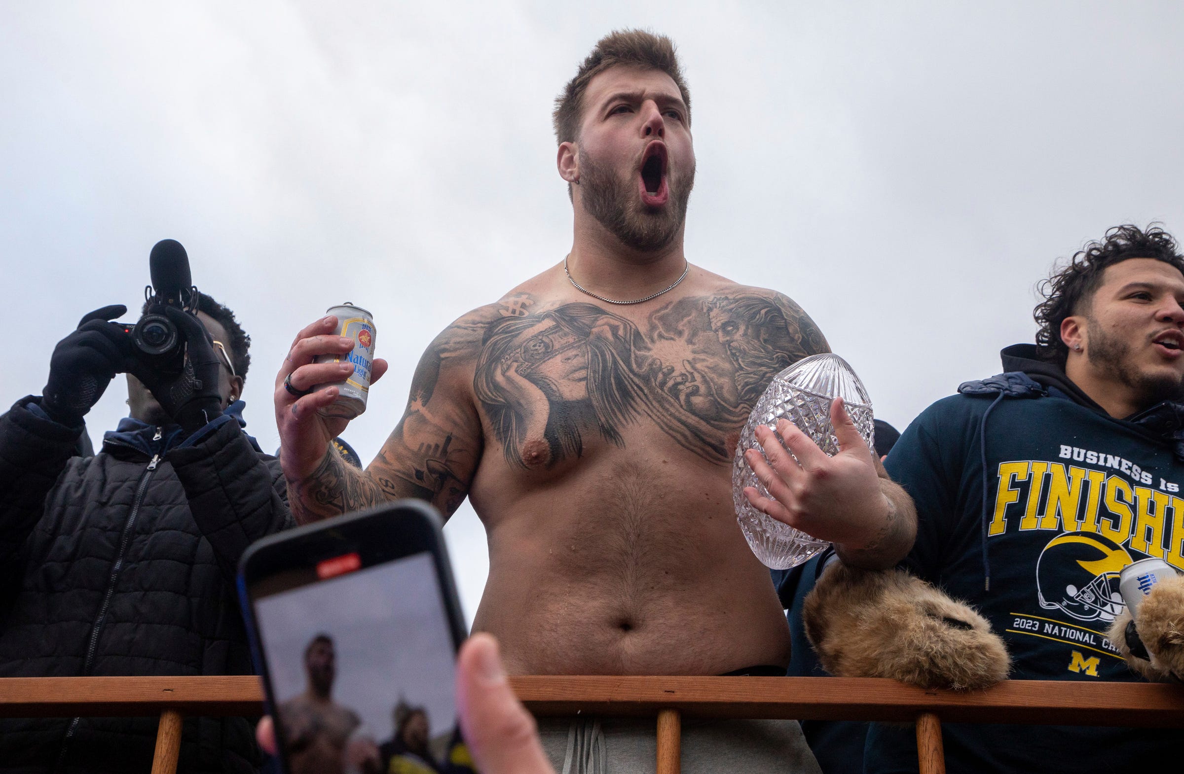 Michigan's Trevor Keegan holds a beer in one hand and the 2023 National Championship trophy in the other during a parade at the University of Michigan campus in Ann Arbor on Saturday, Jan. 13, 2024.