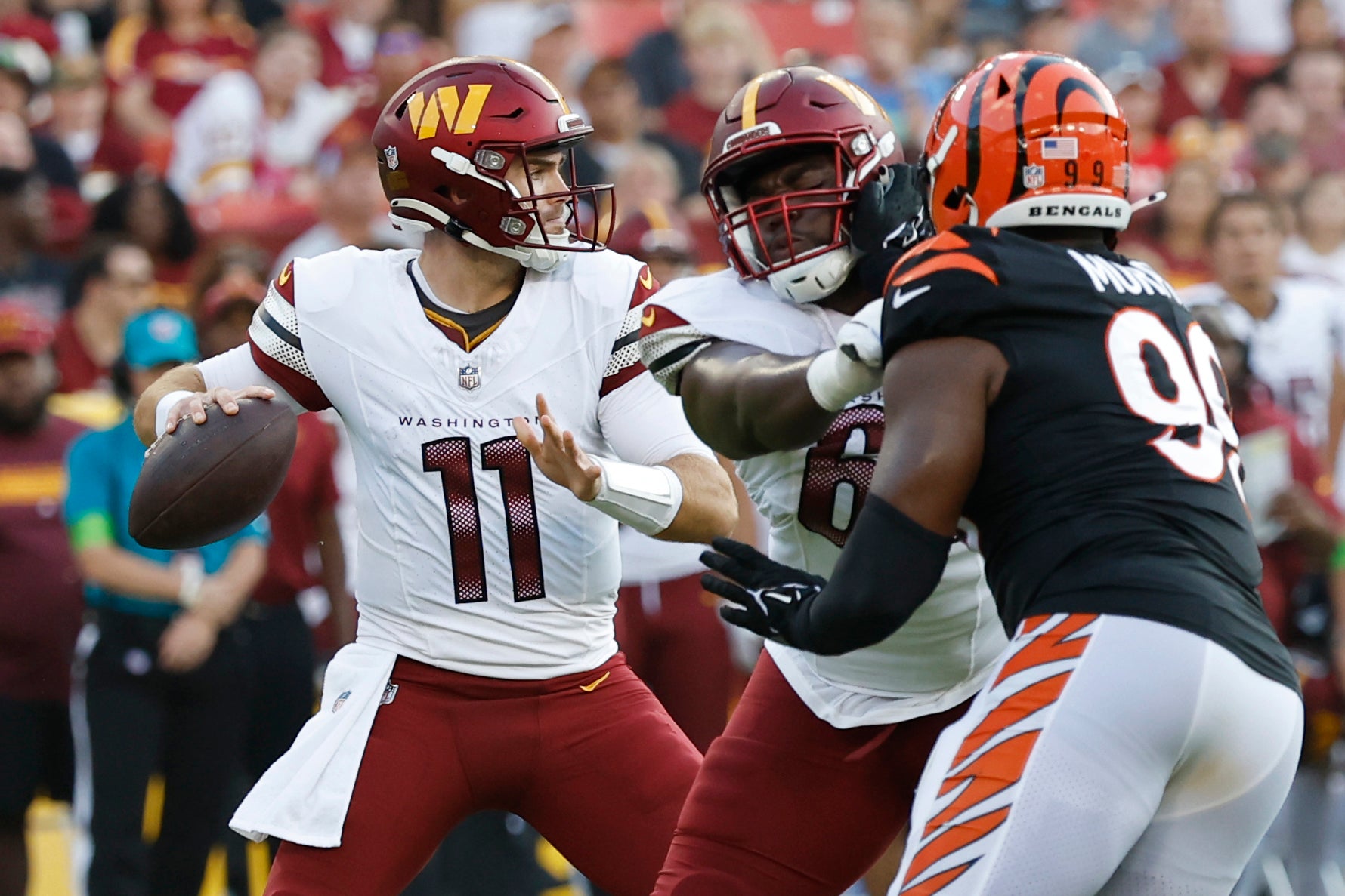 Aug 26, 2023; Landover, Maryland, USA; Washington Commanders quarterback Jake Fromm (11) passes the ball as Cincinnati Bengals defensive end Myles Murphy (99) chases during the second quarter at FedExField.