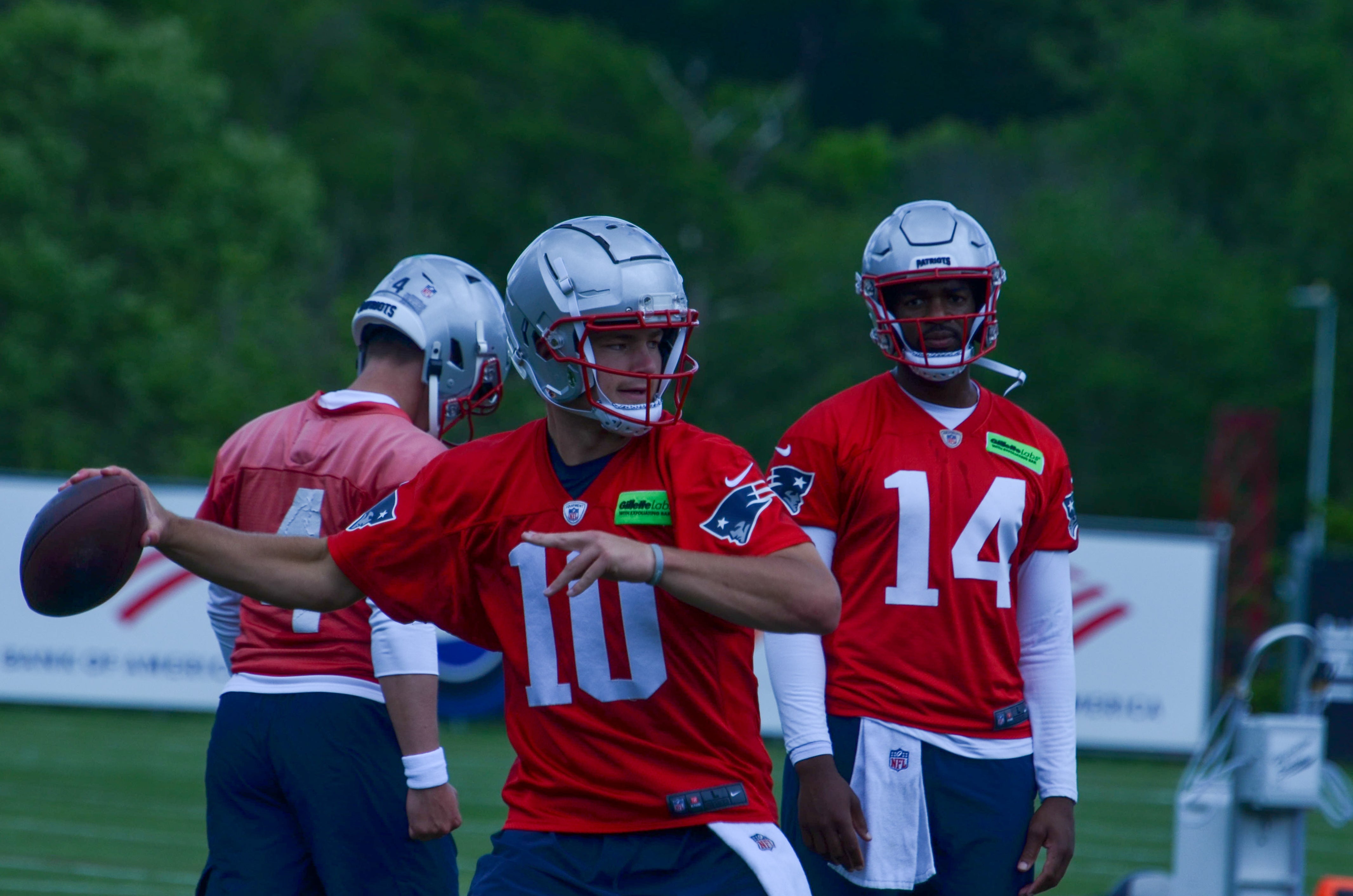 Patriots QB Drake Maye throws the ball while QB Jacoby Brissett looks on at OTAs - May 29, 2024