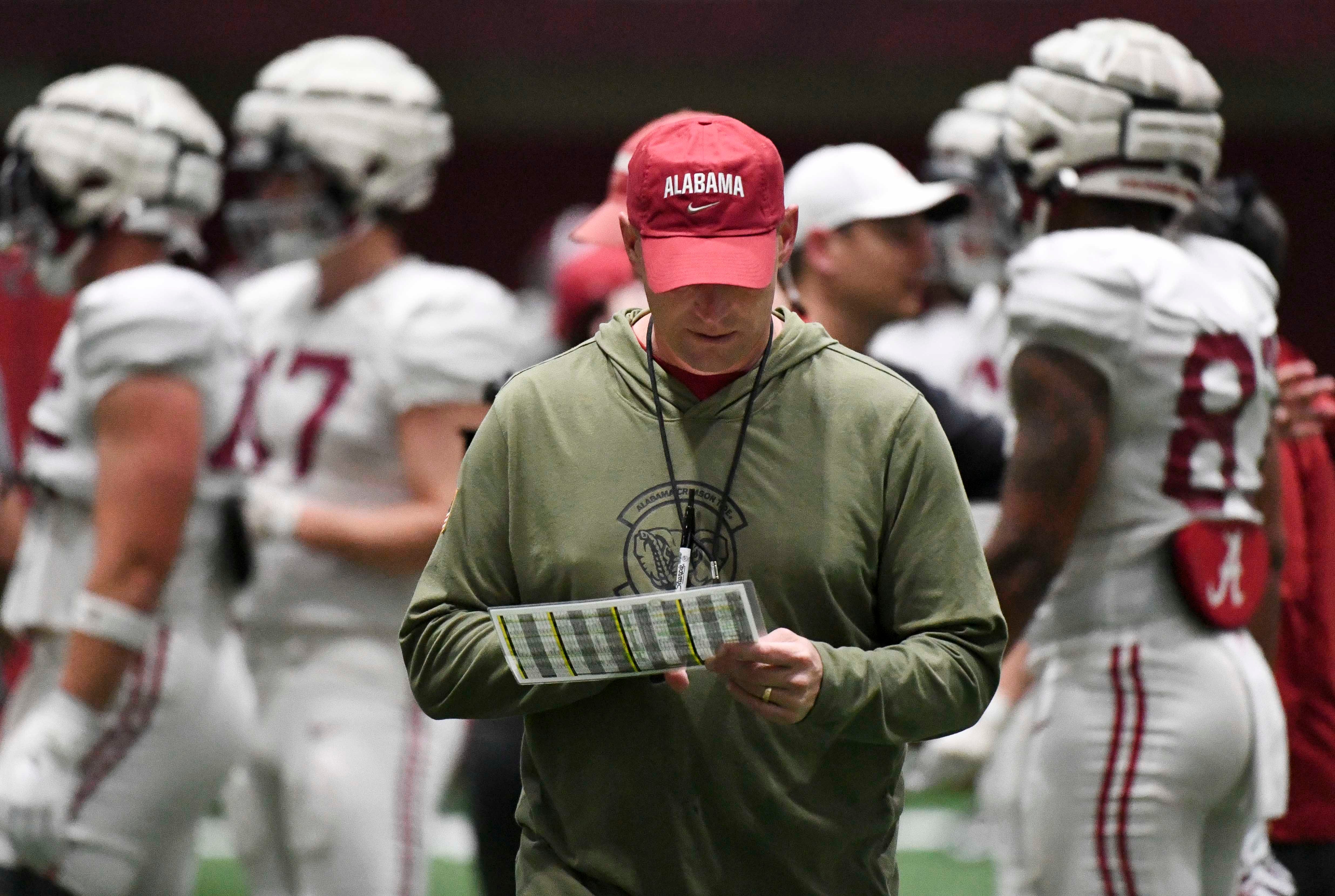 April 9, 2024; Tuscaloosa, Alabama, USA; Alabama head coach Kalen DeBoer checks his play sheet during practice in the Hank Crisp Indoor Practice Facility at the University of Alabama.