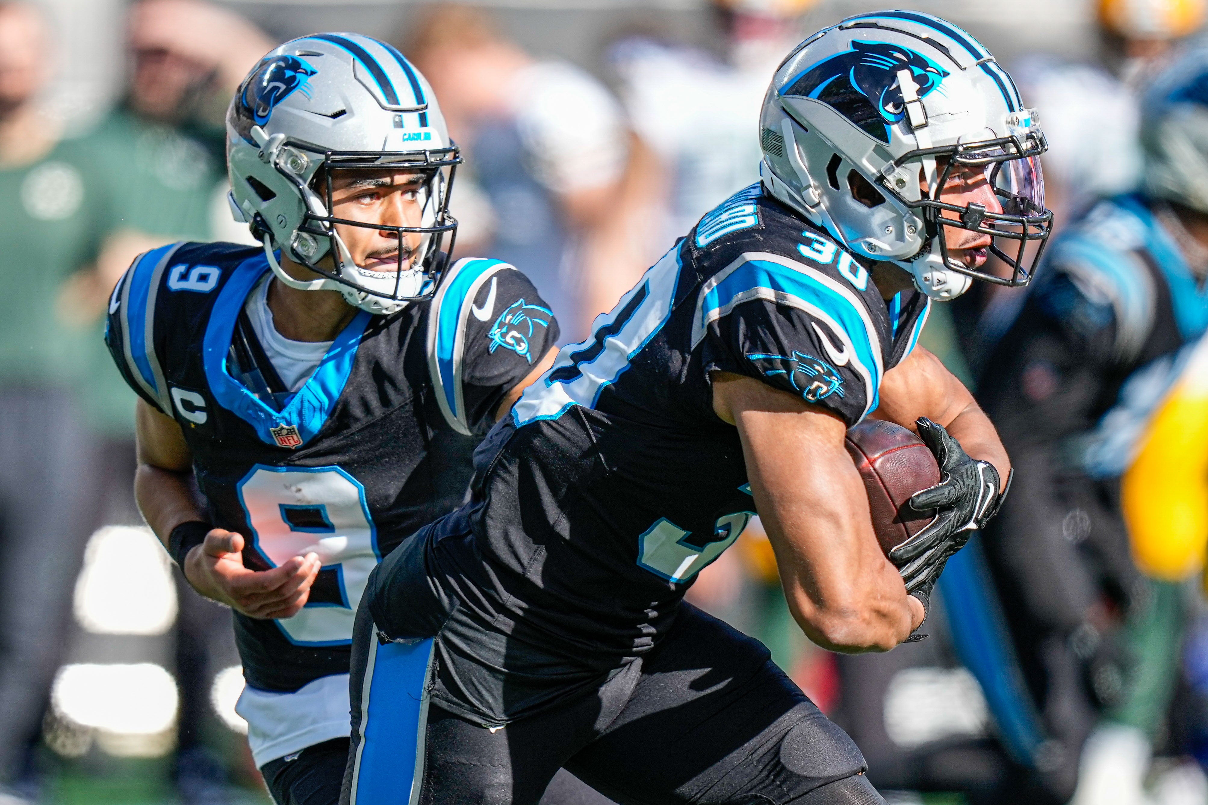 Dec 24, 2023; Charlotte, North Carolina, USA; Carolina Panthers quarterback Bryce Young (9) hands off to running back Chuba Hubbard (30) against the Green Bay Packers during the second quarter at Bank of America Stadium. Mandatory Credit: Jim Dedmon-USA TODAY Sports
