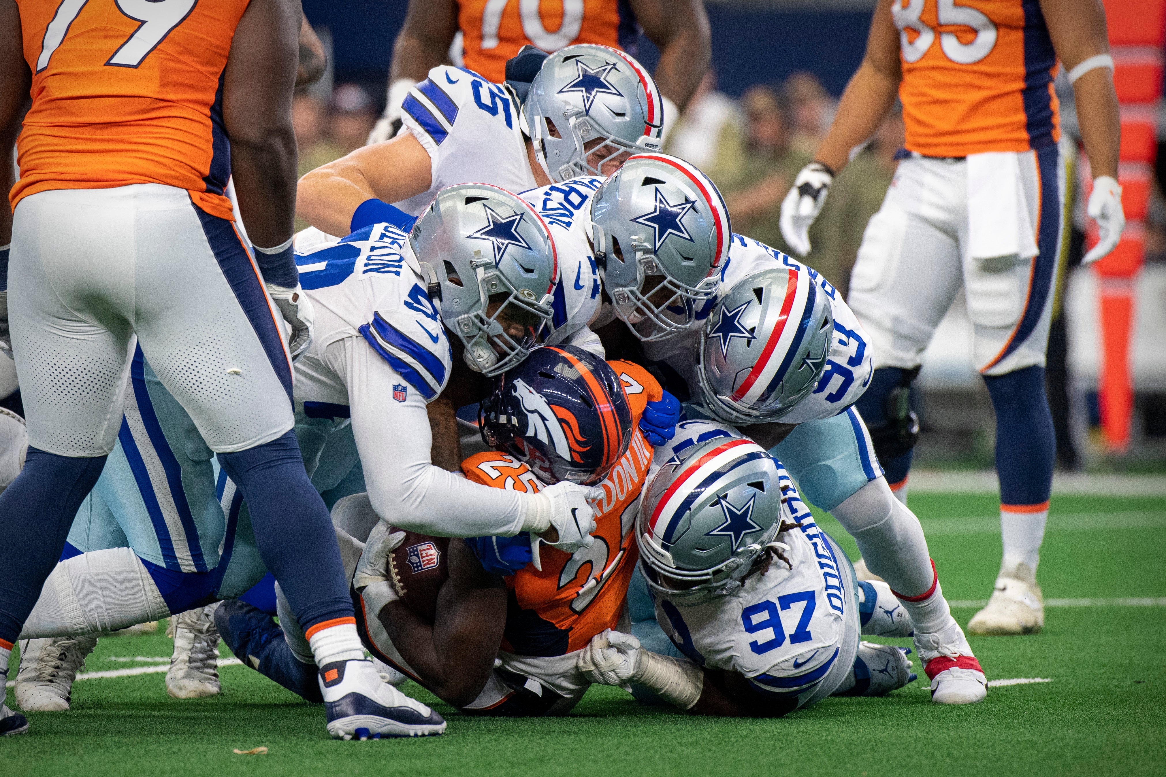 Denver Broncos running back Melvin Gordon III (25) is tackled by Dallas Cowboys defensive tackle Osa Odighizuwa (97) and defensive end Dorance Armstrong (92) and linebacker Micah Parsons (11) and linebacker Leighton Vander Esch (55) and defensive end Chauncey Golston (59) during the game between the Dallas Cowboys and the Denver Broncos at AT&T Stadium.