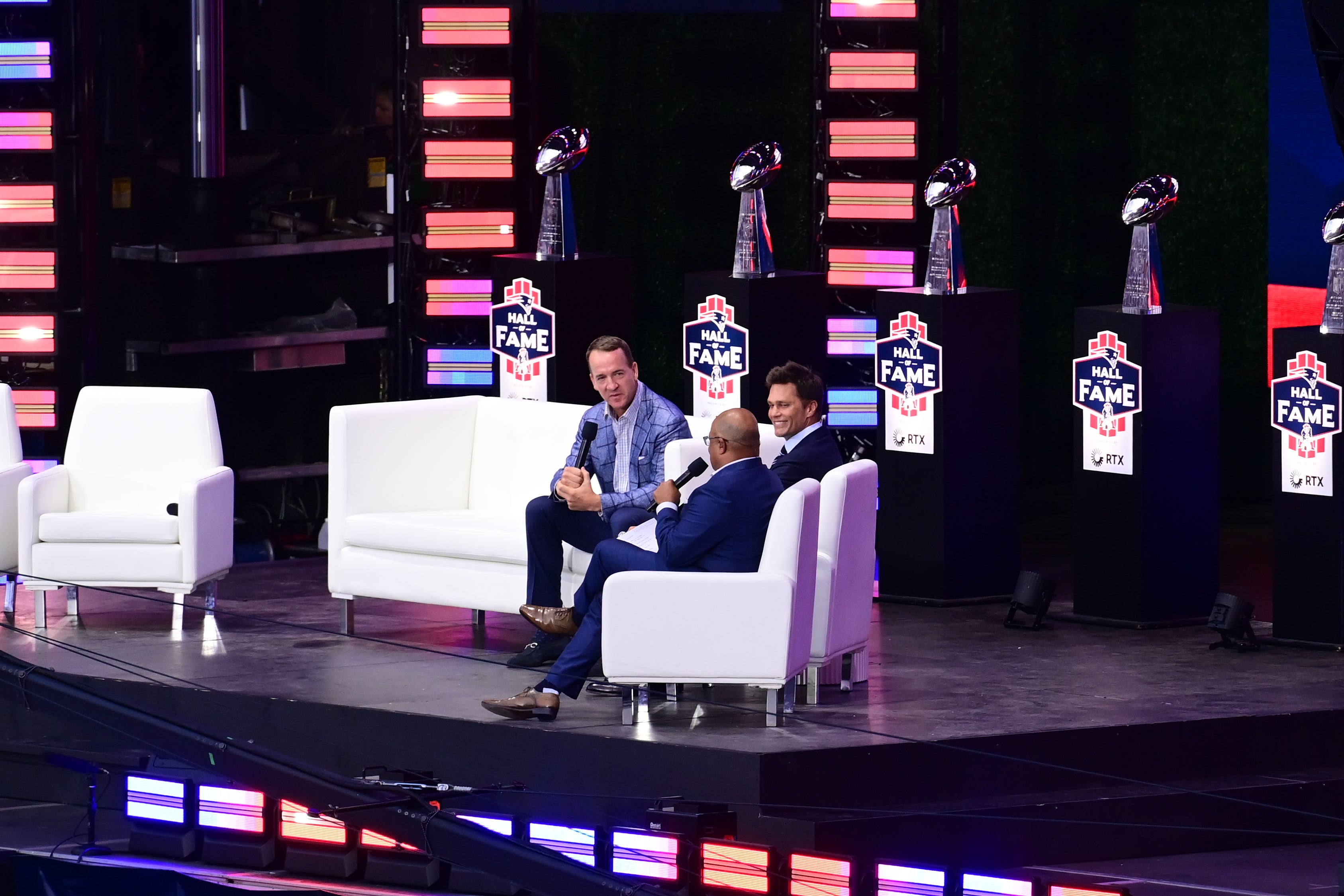 Jun 12, 2024; Foxborough, MA, USA; Retired NFL quarterback Peyton Manning (L) speaks during the New England Patriots Hall of Fame Induction Ceremony for Tom Brady (C) at Gillette Stadium.