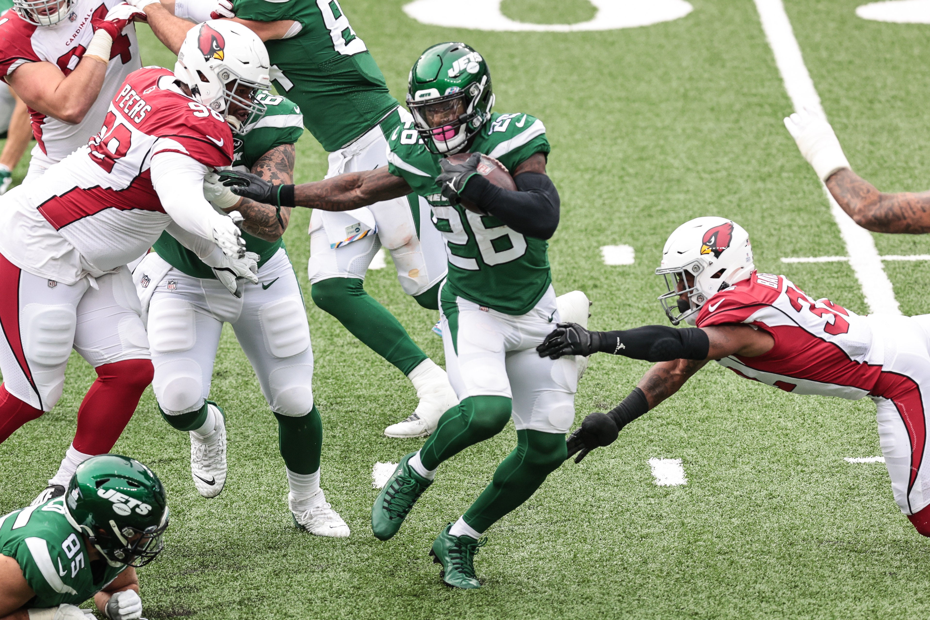 New York Jets running back Le'Veon Bell (26) carries the ball as Arizona Cardinals defensive tackle Corey Peters (98) and strong safety Budda Baker (32) tackle during the second half at MetLife Stadium.