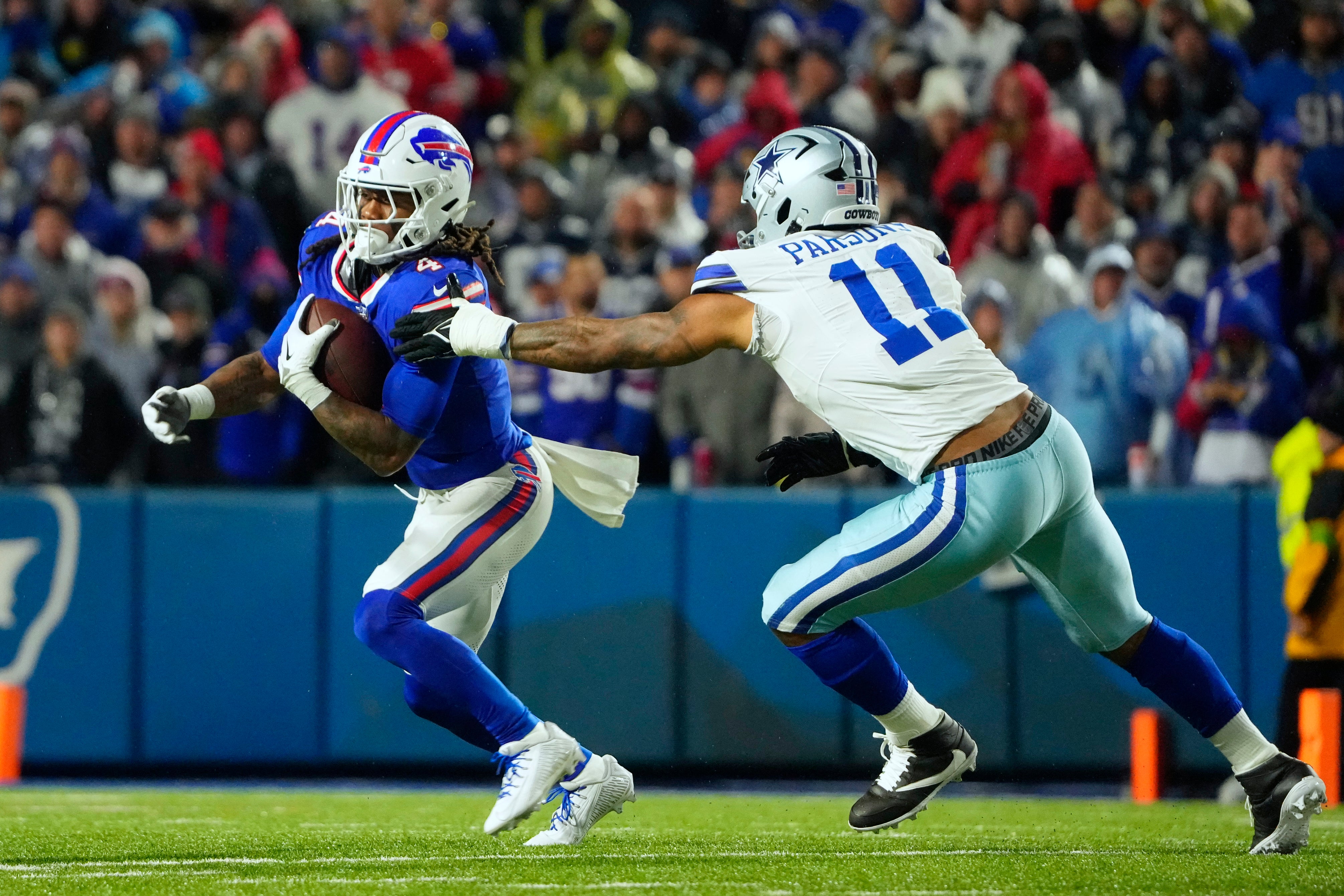 Buffalo Bills running back James Cook (4) runs the ball pressured by Dallas Cowboys linebacker Micah Parsons (11) in the second half at Highmark Stadium.