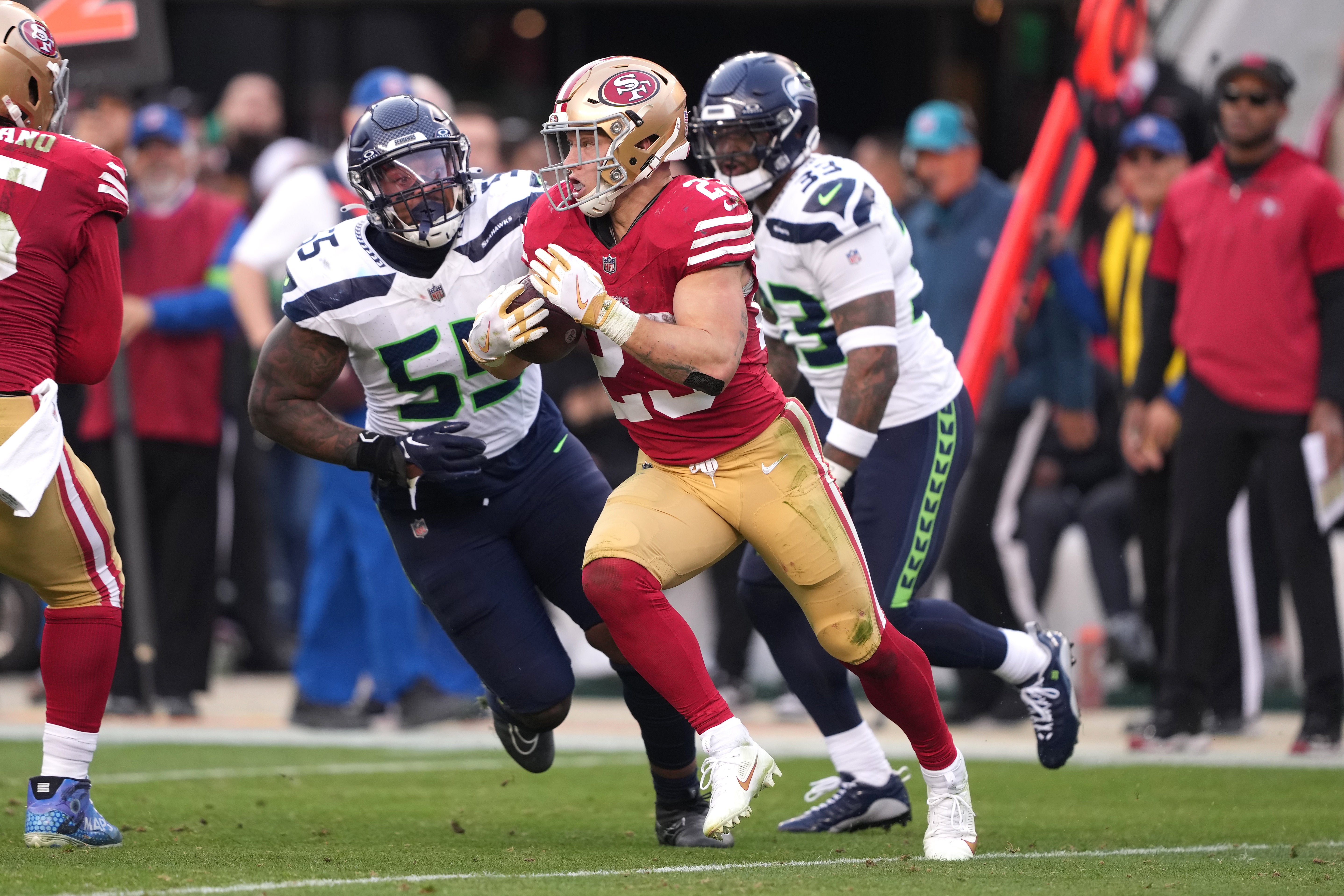 Dec 10, 2023; Santa Clara, California, USA; San Francisco 49ers running back Christian McCaffrey (23) carries the ball against Seattle Seahawks defensive end Dre'Mont Jones (55) and safety Jamal Adams (33) during the fourth quarter at Levi's Stadium.