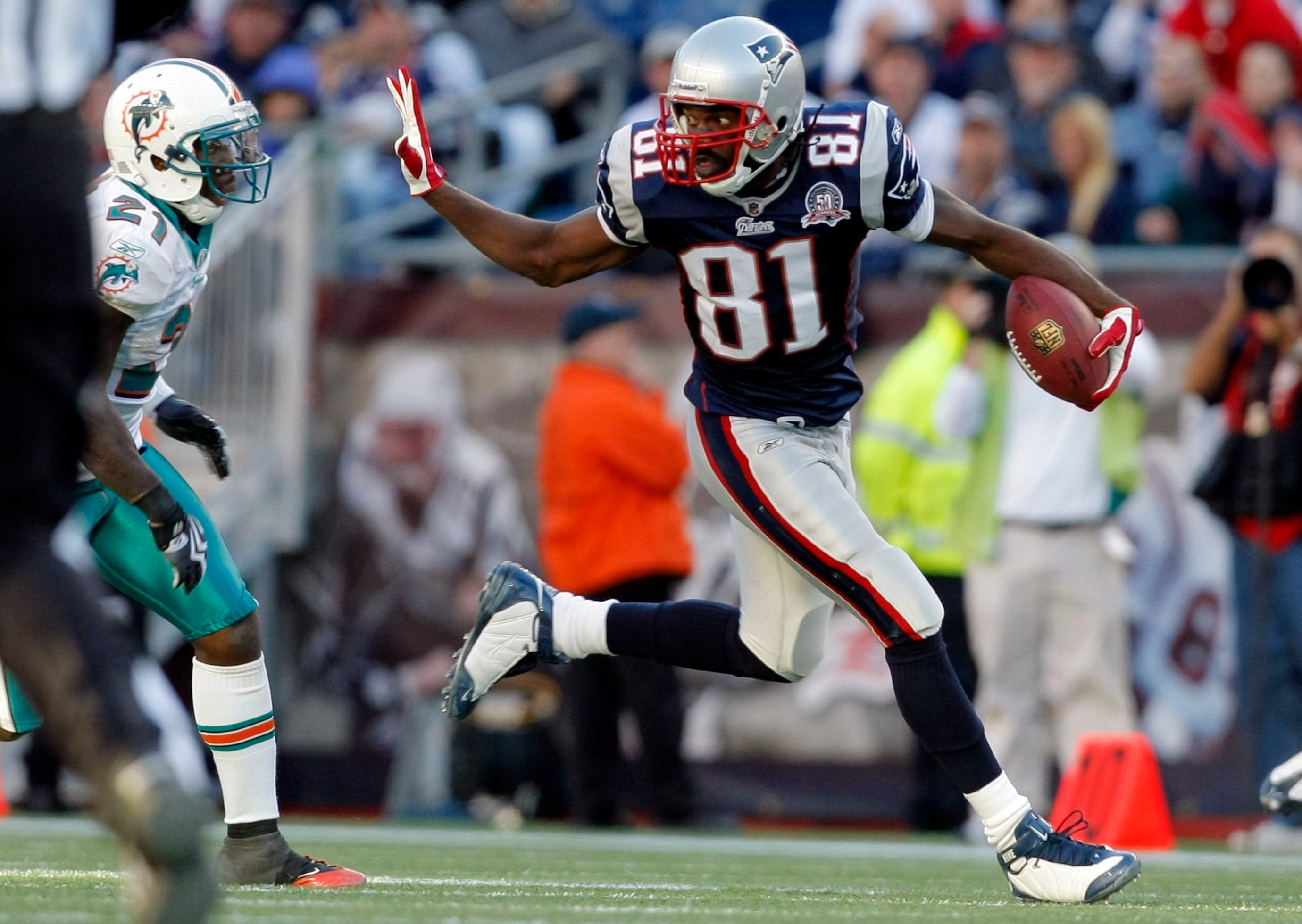 Nov 8, 2009; Foxborough, MA, USA; New England Patriots wide receiver Randy Moss (81) holds off Miami Dolphins cornerback Vontae Davis (21) as he runs for a touchdown during the third quarter at Gillette Stadium. The Patriots defeated Miami 27-17.