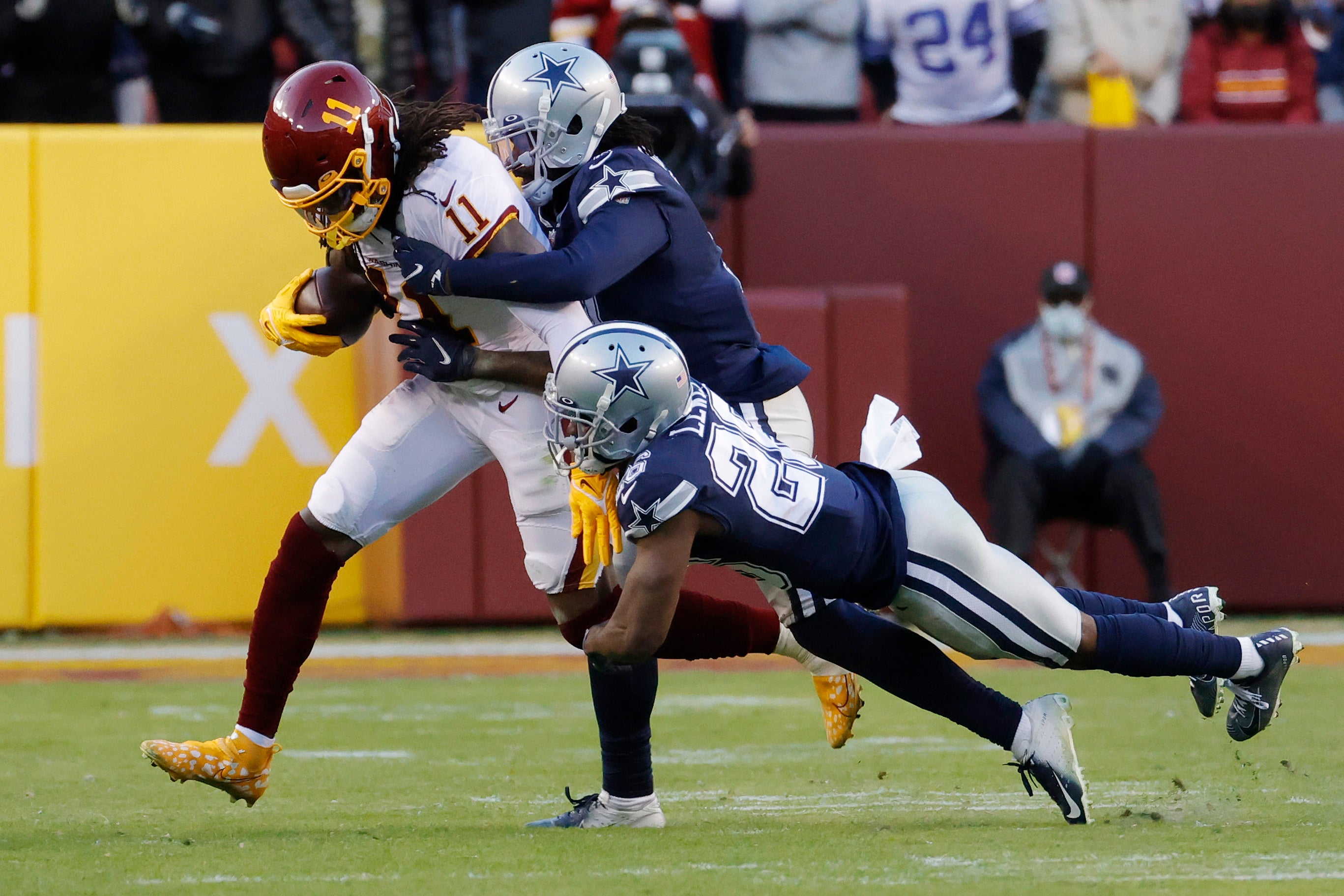 Washington Football Team wide receiver Cam Sims (11) runs with the ball as Dallas Cowboys cornerback Trevon. Diggs (7) and Cowboys cornerback Jourdan Lewis (26) make the tackle during the fourth quarter at FedExField.