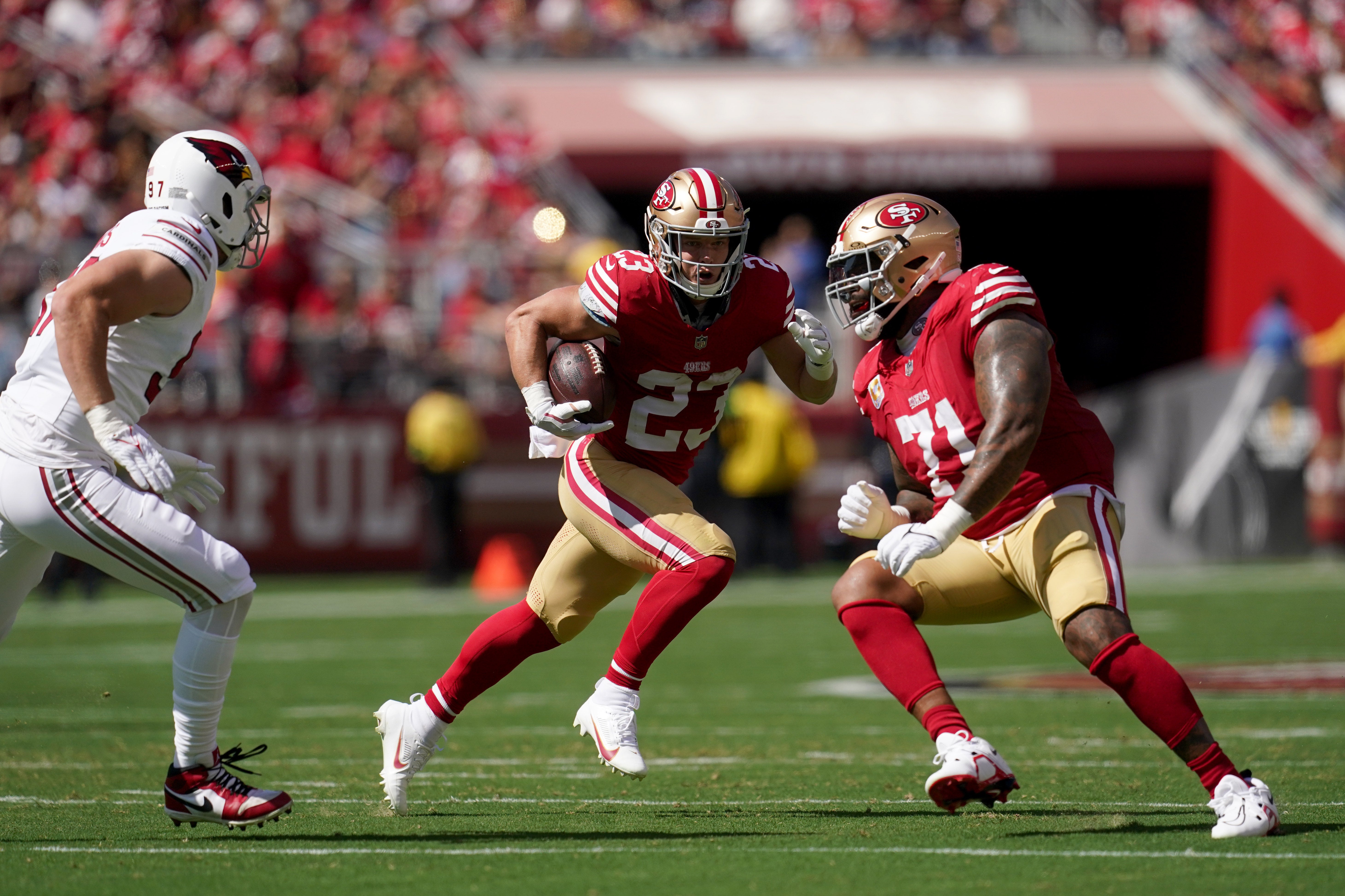 Oct 1, 2023; Santa Clara, California, USA; San Francisco 49ers running back Christian McCaffrey (23) runs the ball behind offensive tackle Trent Williams (71) against the Arizona Cardinals in the first quarter at Levi's Stadium.