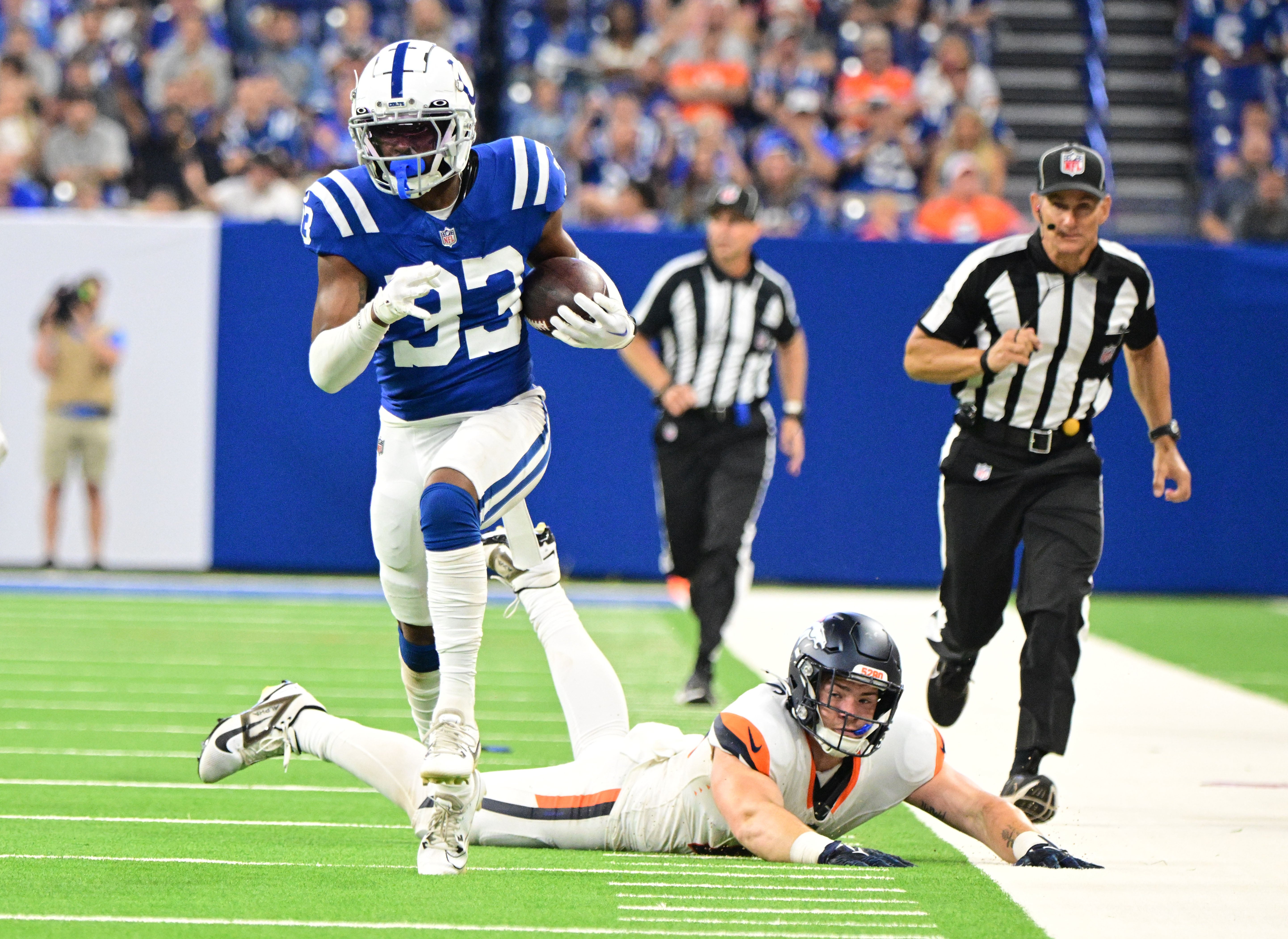Aug 11, 2024; Indianapolis, Indiana, USA; Indianapolis Colts cornerback Micah Abraham (33) runs past Denver Broncos tight end Nate Adkins (45) for a touchdown during the second half at Lucas Oil Stadium.