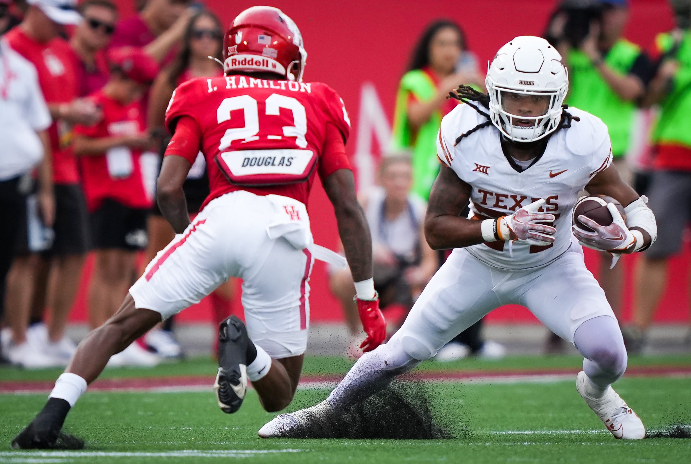 Texas running back Jonathon Brooks (24) dodges around Houston defensive back Isaiah Hamilton (23) in the third quarter of the Longhorn's game against the Houston Cougars at TDECU Stadium in Houston, Saturday, Oct. 21, 2023. Texas won the game 31-24.