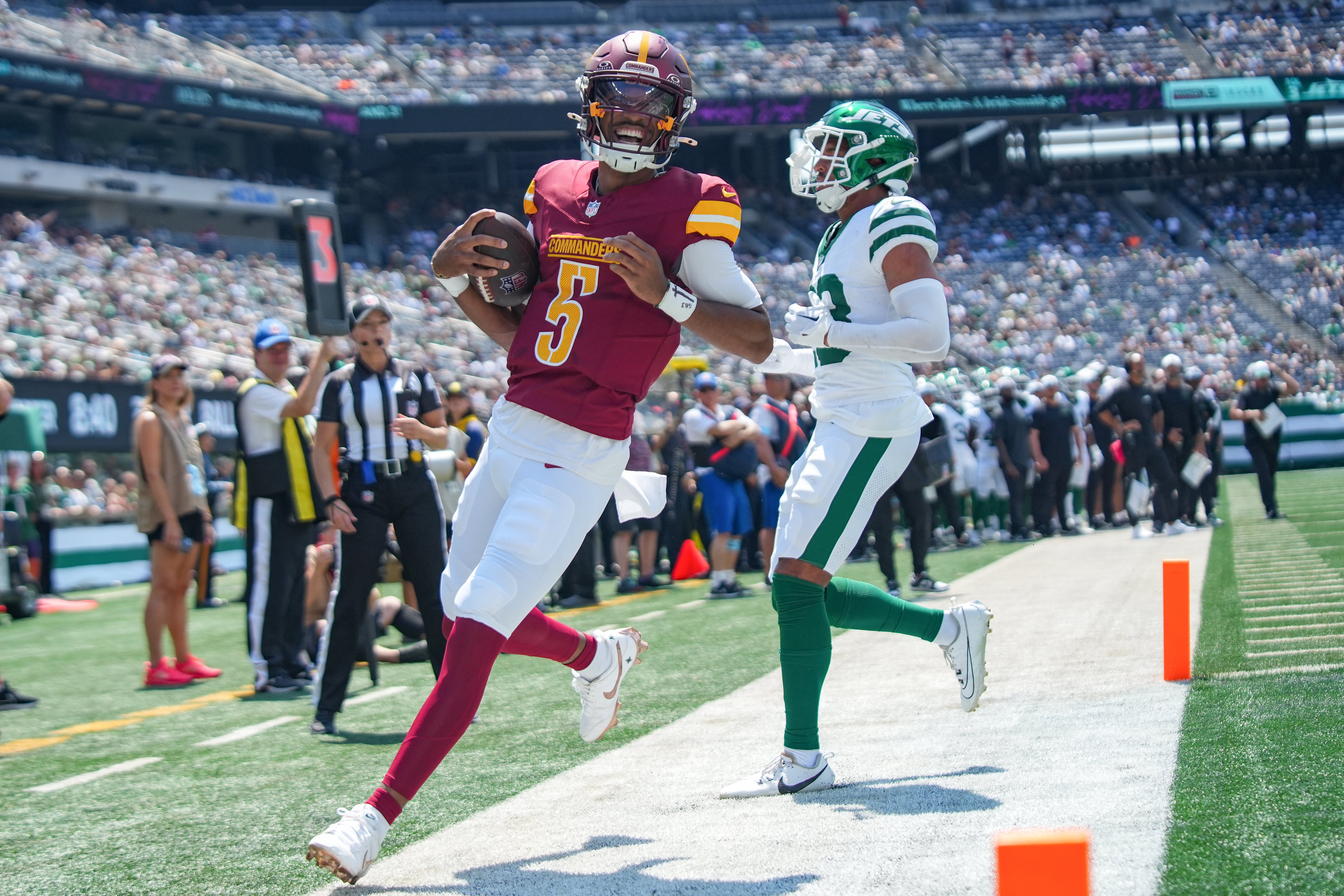 Aug 10, 2024; East Rutherford, New Jersey, USA; Washington Commanders quarterback Jayden Daniels (5) rushes for a touchdown during the first quarter against the New York Jets at MetLife Stadium. Mandatory Credit: Lucas Boland-USA TODAY Sports