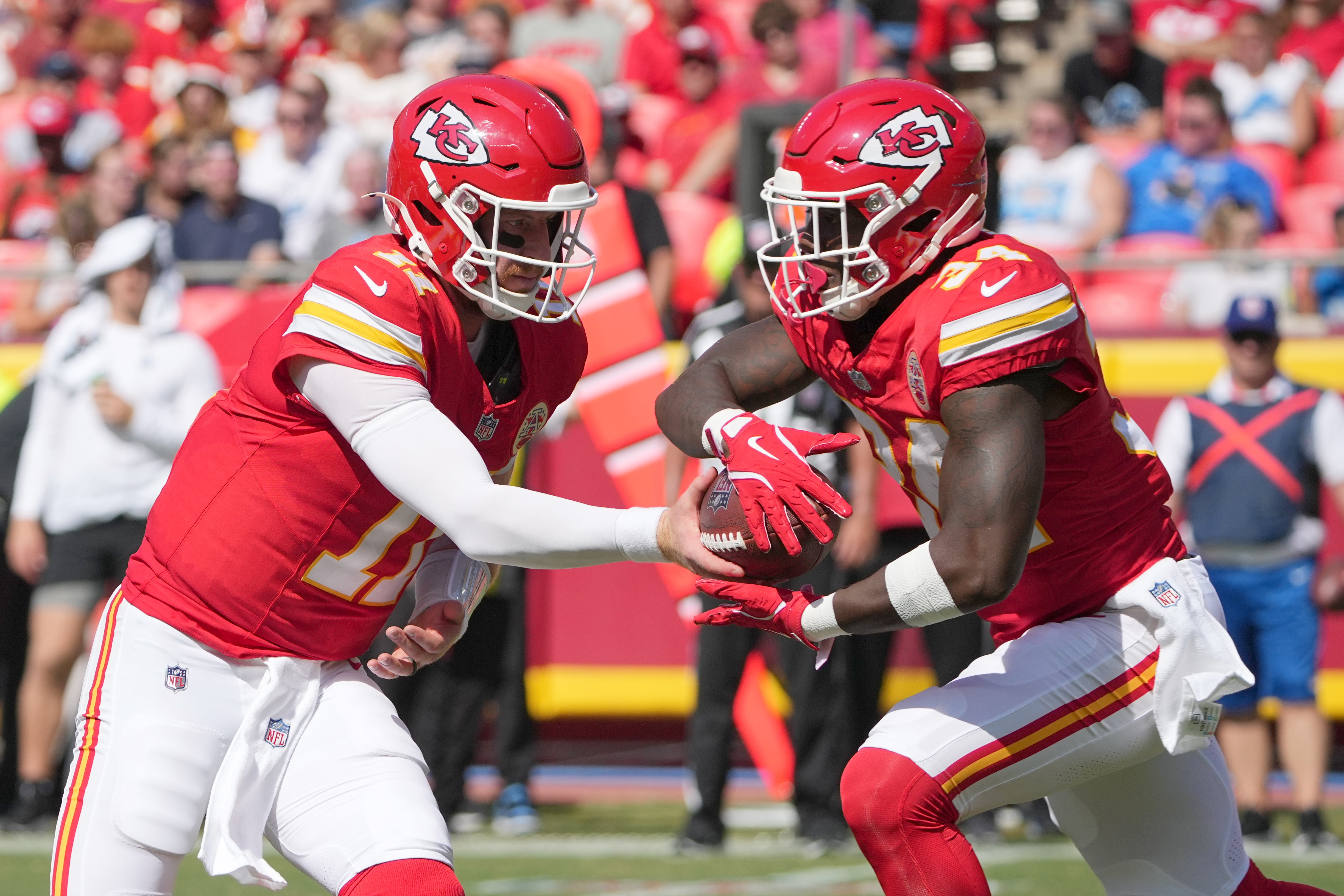 Aug 17, 2024; Kansas City, Missouri, USA; Kansas City Chiefs quarterback Carson Wentz (11) hands off to running back Deneric Prince (34) against the Detroit Lions during the first half at GEHA Field at Arrowhead Stadium.