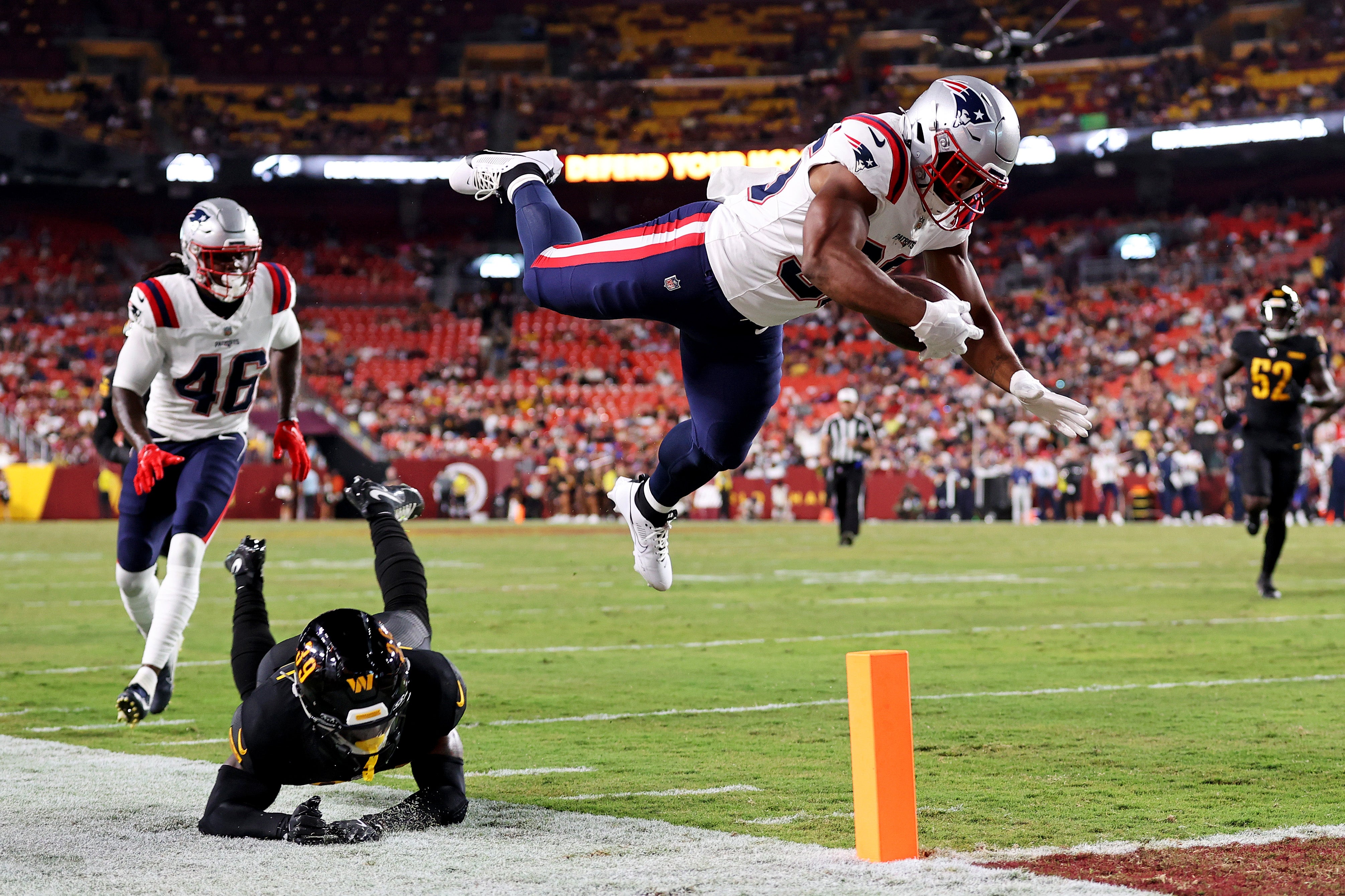 Aug 25, 2024; Landover, Maryland, USA; New England Patriots running back Kevin Harris (36) dives for a touchdown against Washington Commanders safety Jeremy Reaves (39) during the first quarter during a preseason game at Commanders Field.