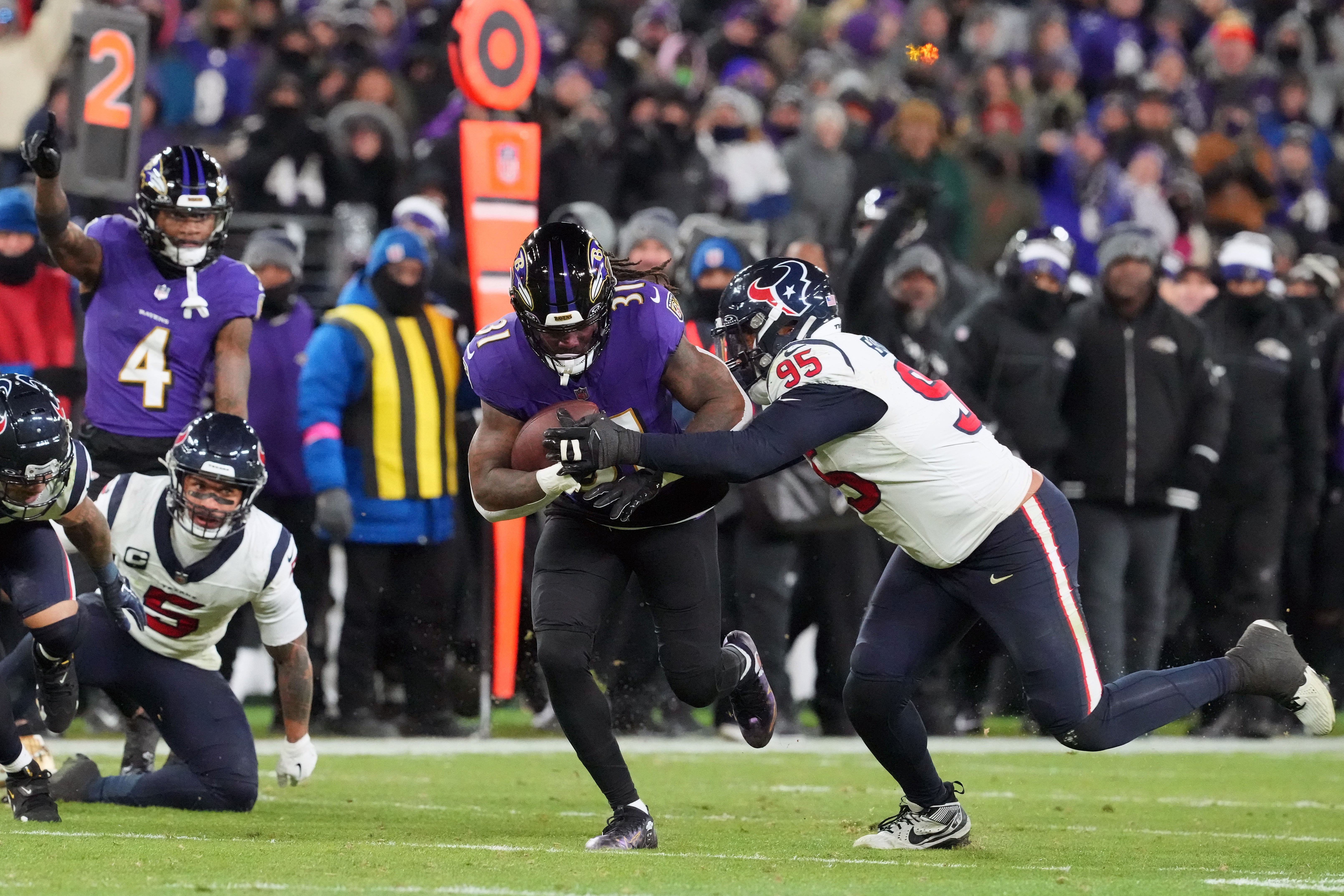 Baltimore Ravens running back Dalvin Cook (31) runs the ball against Houston Texans defensive end Derek Barnett (95) during the fourth quarter of a 2024 AFC divisional round game at M&T Bank Stadium.