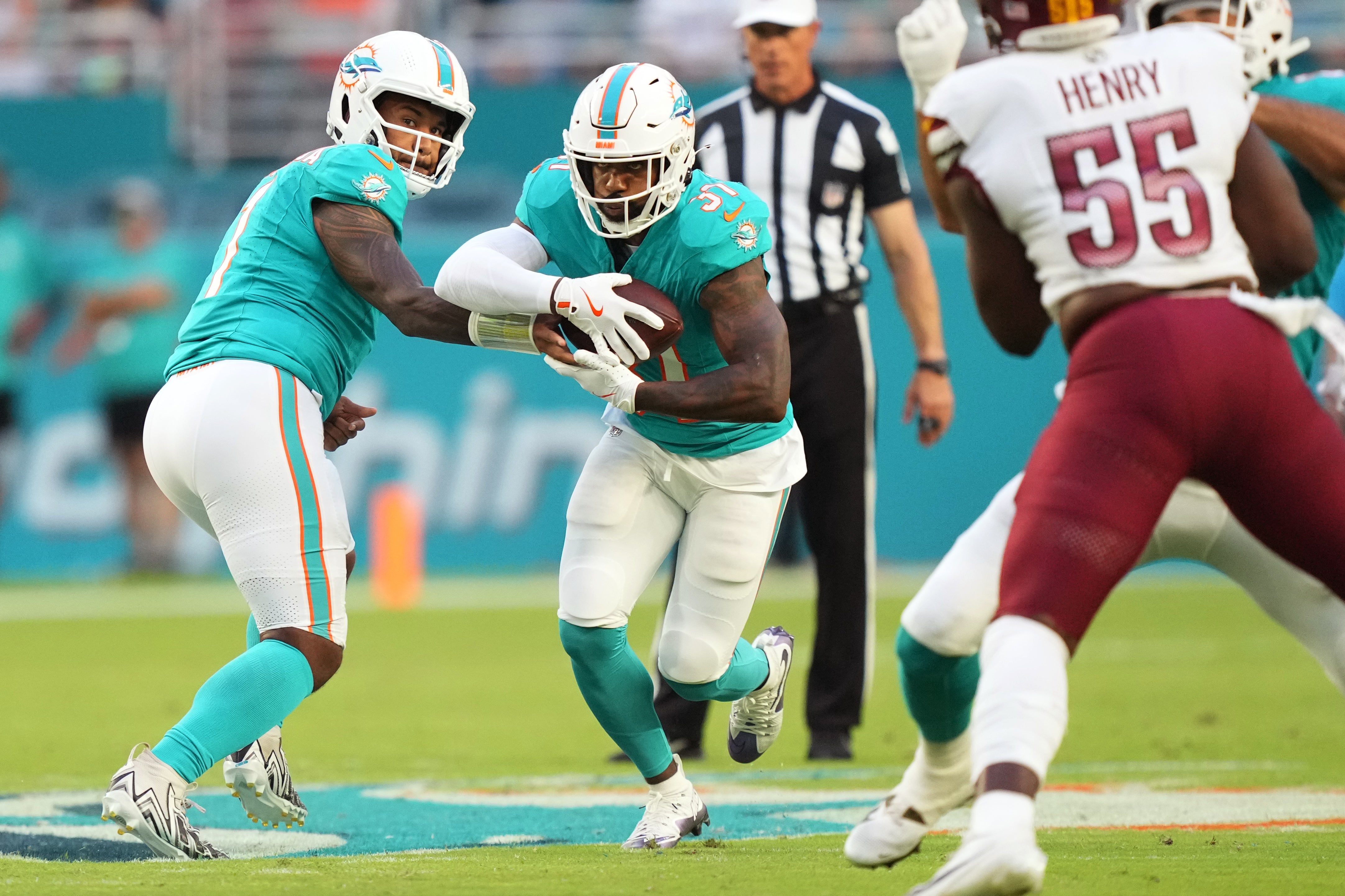 Aug 17, 2024; Miami Gardens, Florida, USA; Miami Dolphins quarterback Tua Tagovailoa (1) hands off to running back Raheem Mostert (31) against the Washington Commanders during the first quarter at Hard Rock Stadium.