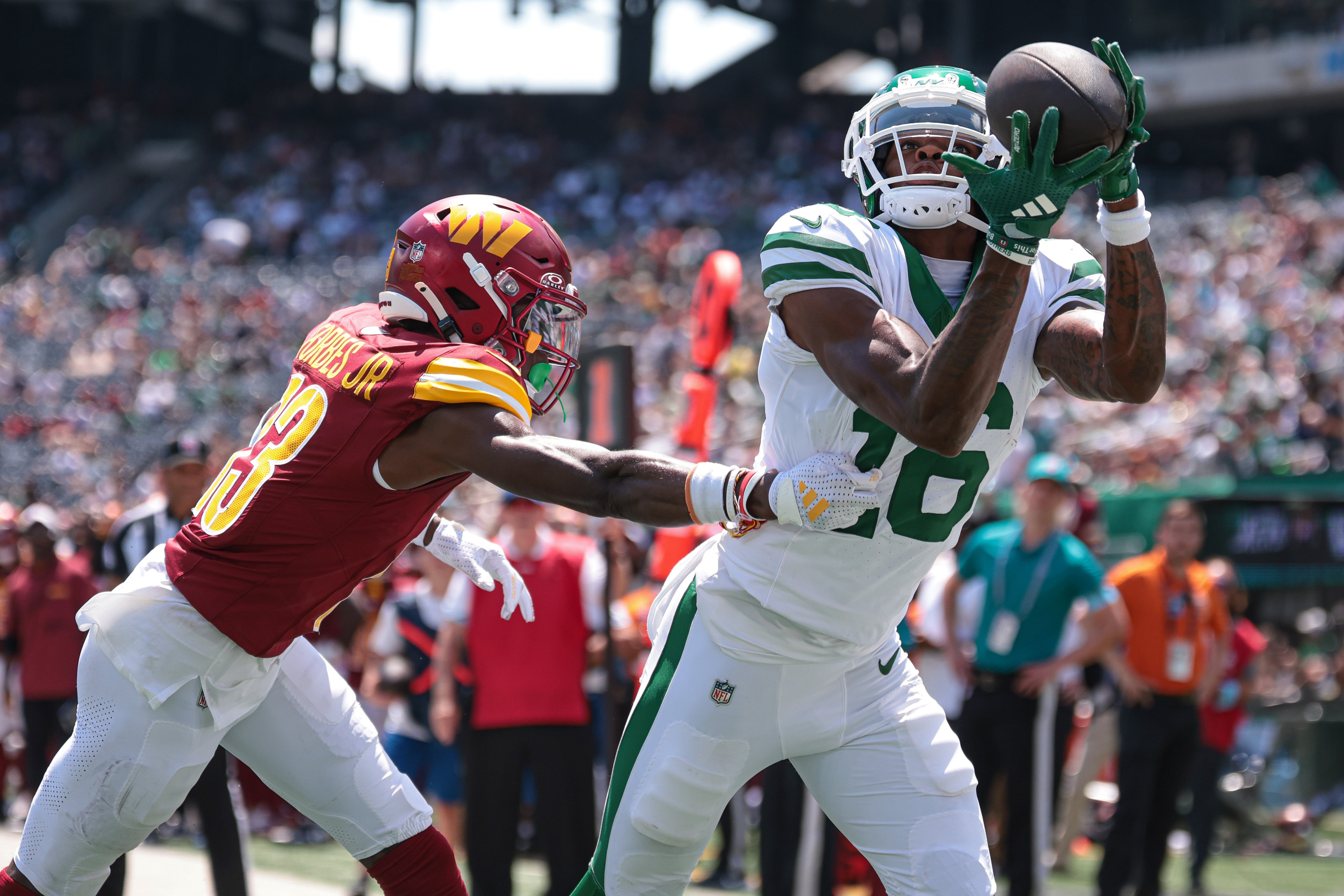 New York Jets wide receiver Jason Brownlee (16) catches a touchdown pass during the first half as Washington Commanders cornerback Chigozie Anusiem (23) defends at MetLife Stadium.