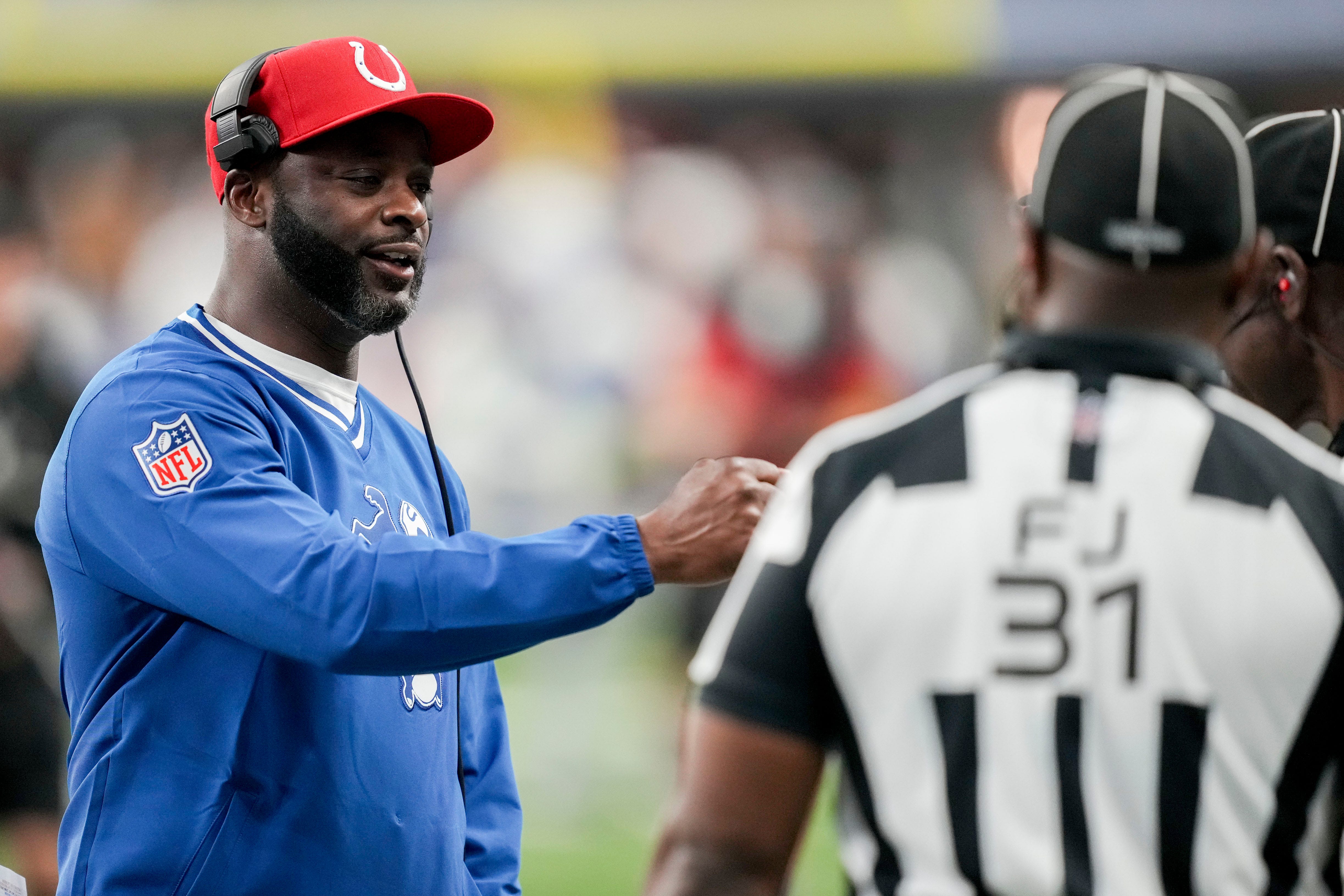 Indianapolis Colts wide receivers coach Reggie Wayne fist bumps an official Saturday, Dec. 16, 2023, before a game against the Pittsburgh Steelers at Lucas Oil Stadium in Indianapolis.