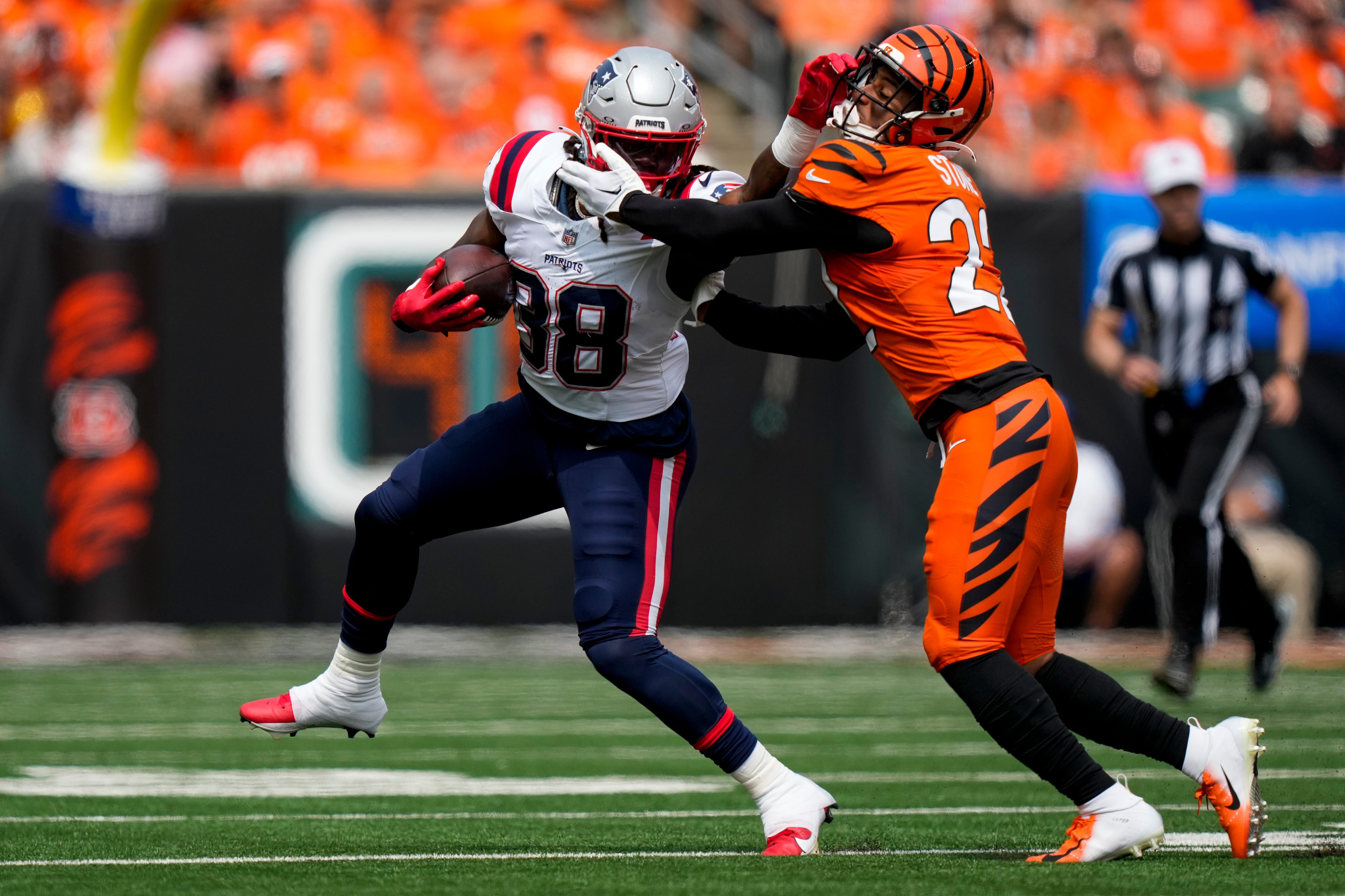 Sep 8, 2024; Cincinnati, Ohio, USA; New England Patriots running back Rhamondre Stevenson (38) breaks a tackle from Cincinnati Bengals safety Geno Stone (22) on a carry in the first quarter of the NFL Week 1 game between the Cincinnati Bengals and the New England Patriots at Paycor Stadium.