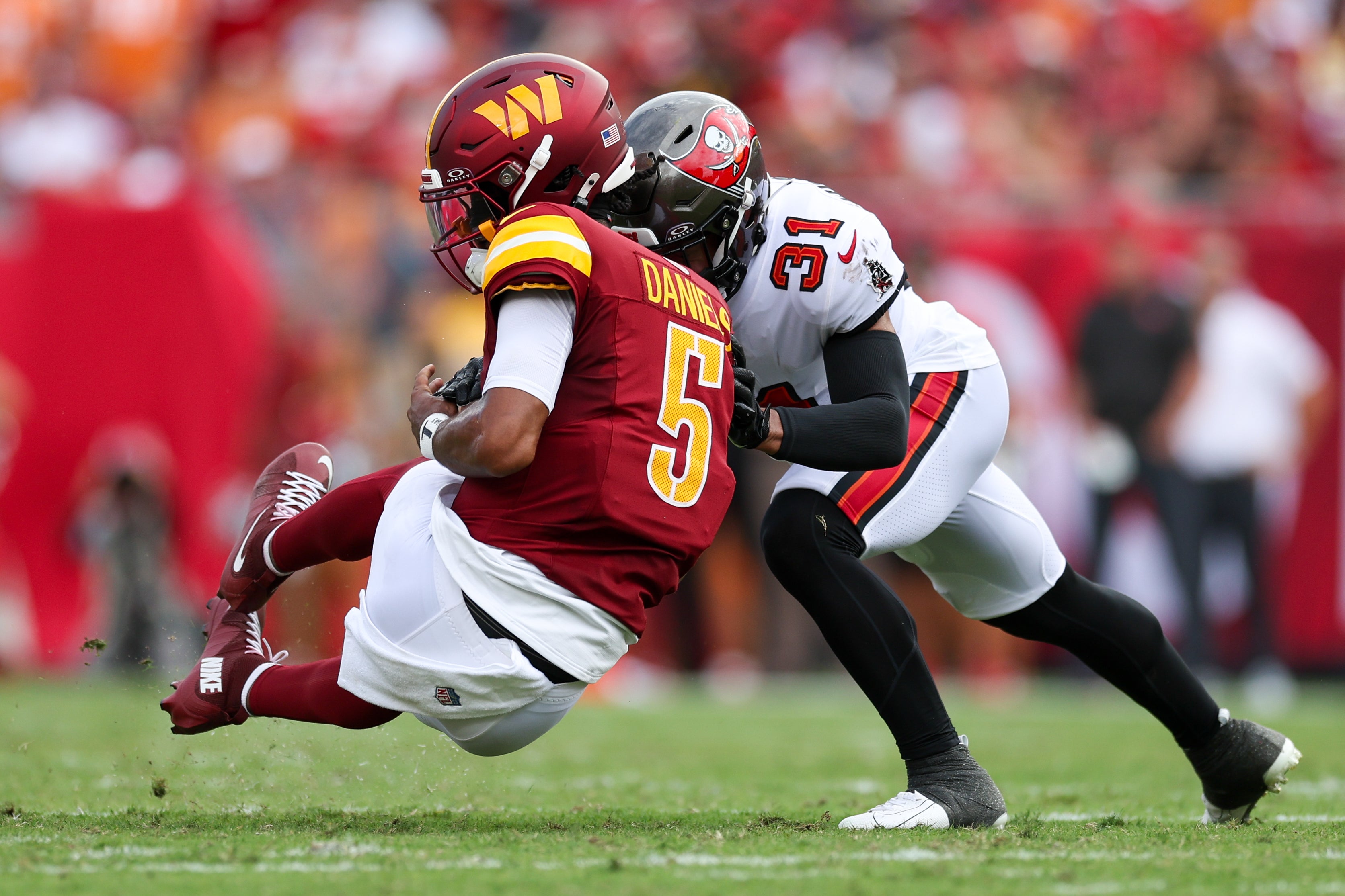 Sep 8, 2024; Tampa, Florida, USA; Washington Commanders quarterback Jayden Daniels (5) is hit by Tampa Bay Buccaneers safety Antoine Winfield Jr. (31) in the second quarter at Raymond James Stadium.