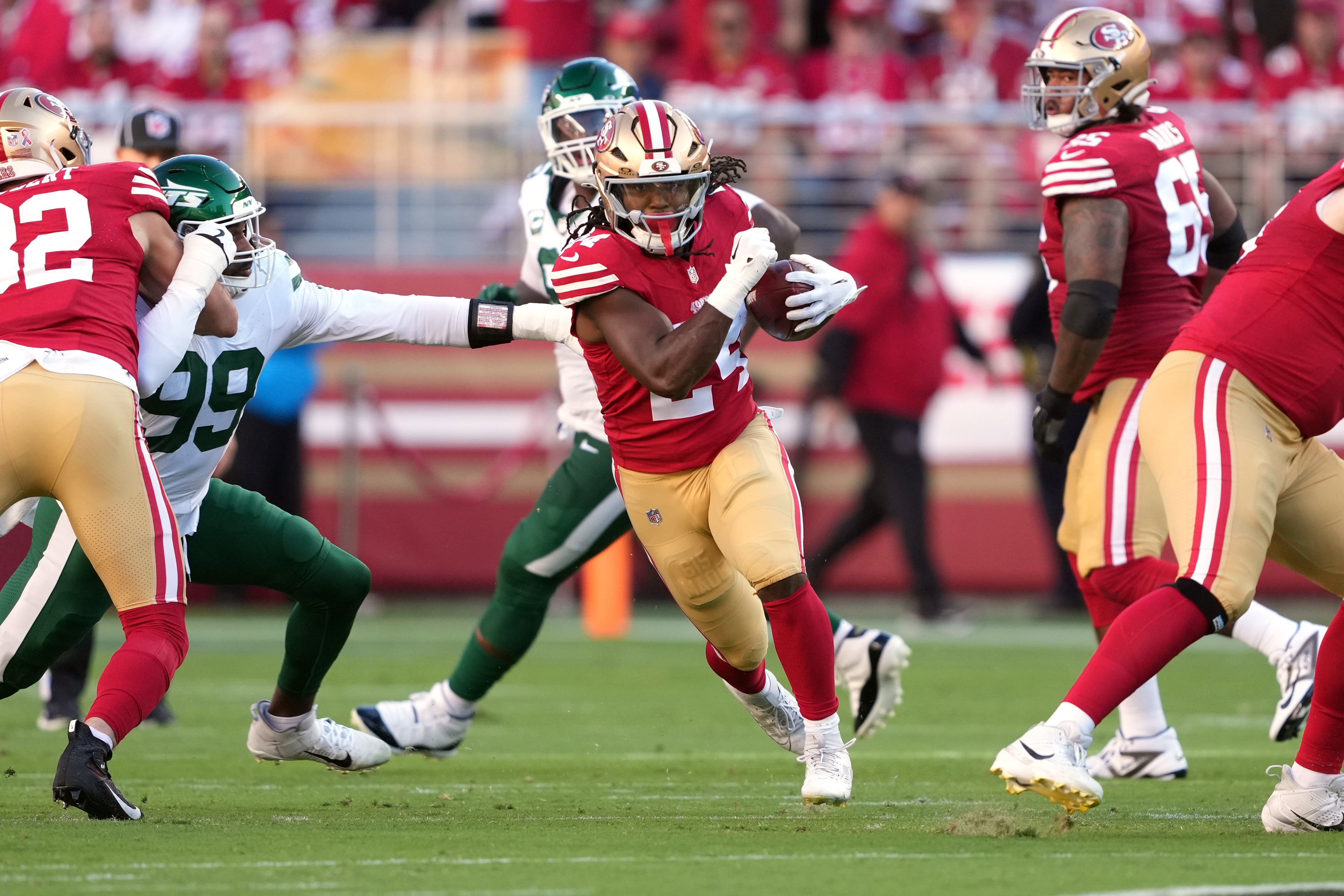 San Francisco 49ers running back Jordan Mason (center) carries the ball against New York Jets defensive end Will McDonald IV (99) during the first quarter at Levi's Stadium.