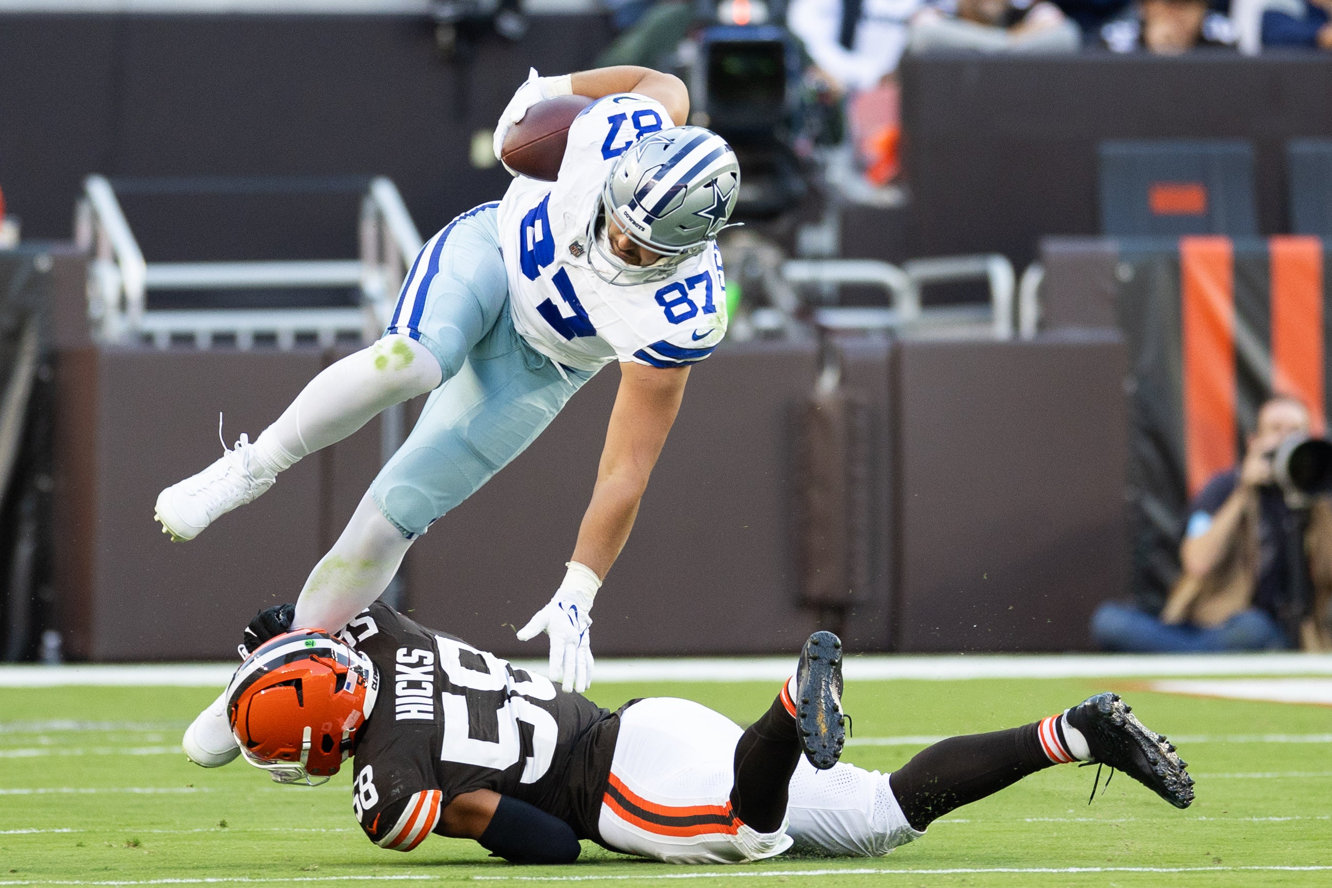 Dallas Cowboys tight end Jake Ferguson (87) falls over Cleveland Browns linebacker Jordan Hicks (58) as he is tackled around his ankle during the third quarter at Huntington Bank Field.