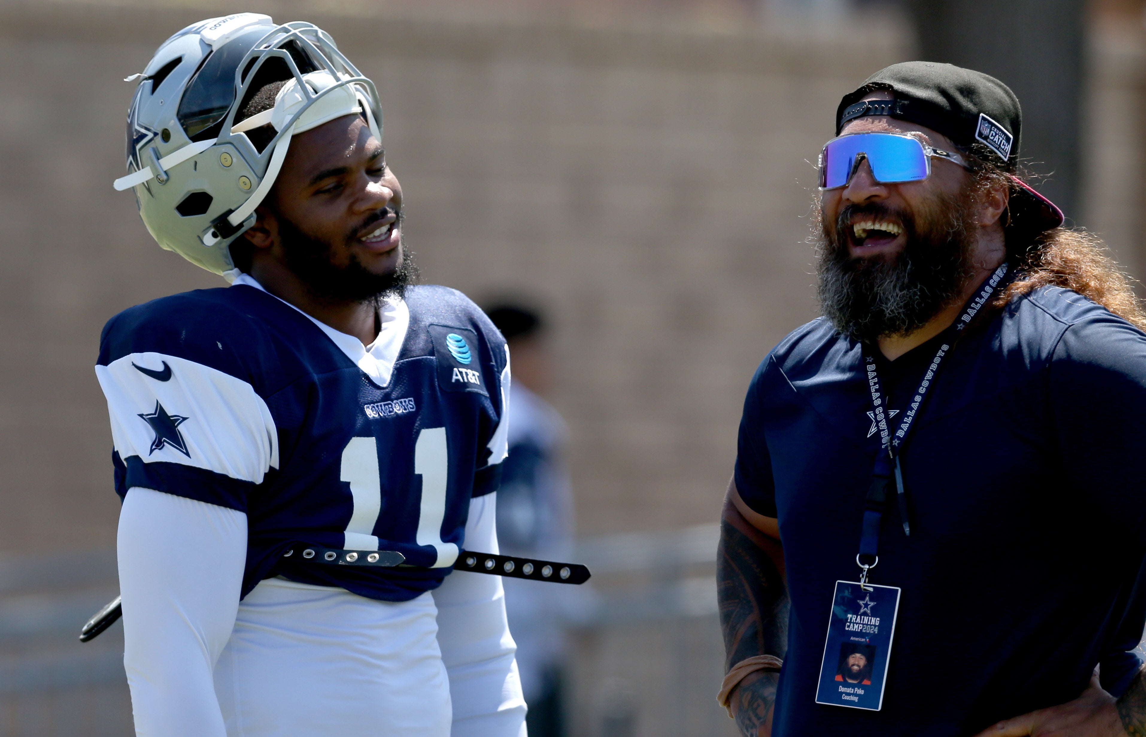 Dallas Cowboys linebacker Micah Parsons (11) talks to assistant coach Domata Peko during training camp at the River Ridge Playing Fields in Oxnard, California.