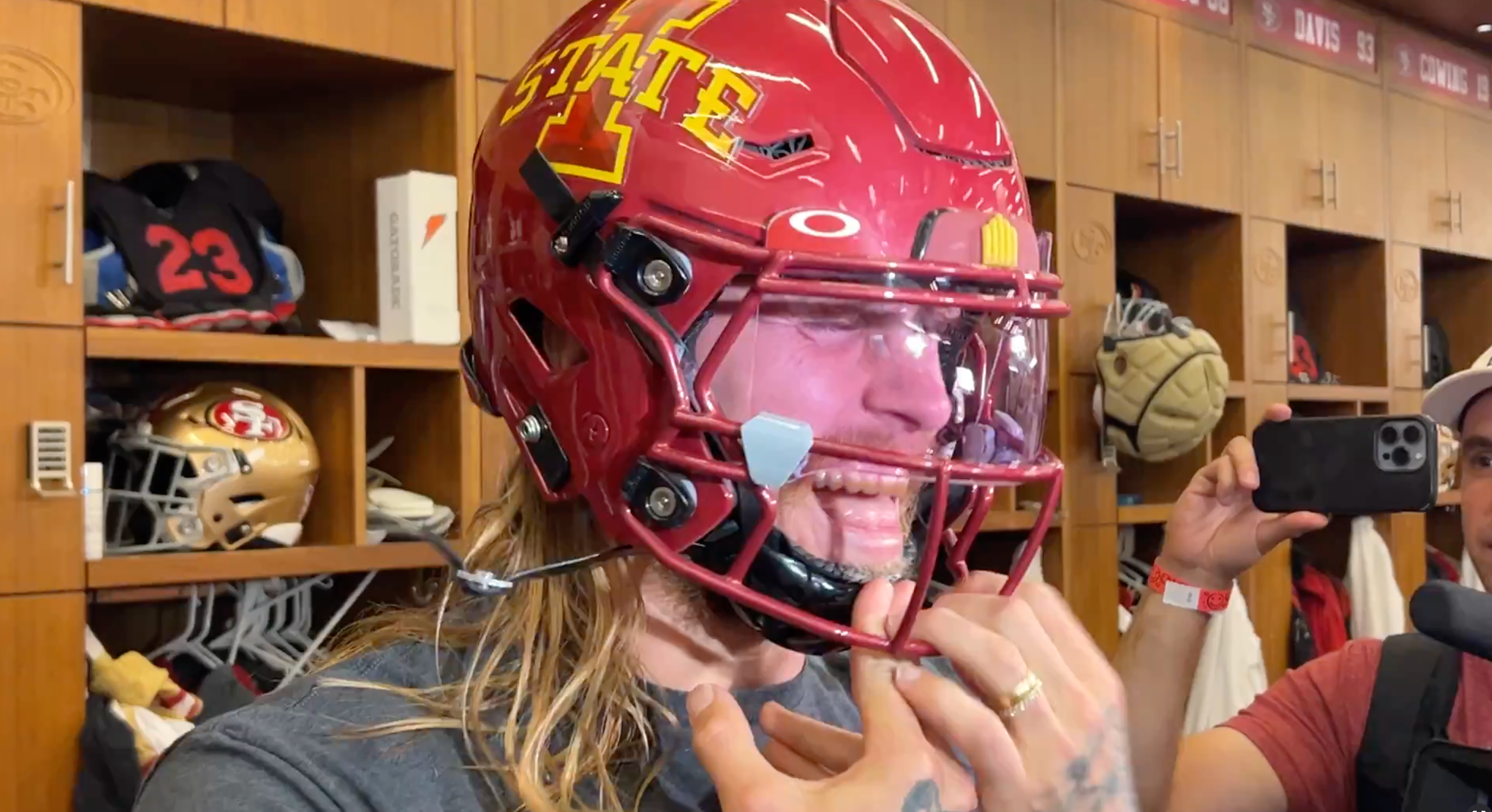 George Kittle wears an Iowa State helmet in the 49ers' locker room.