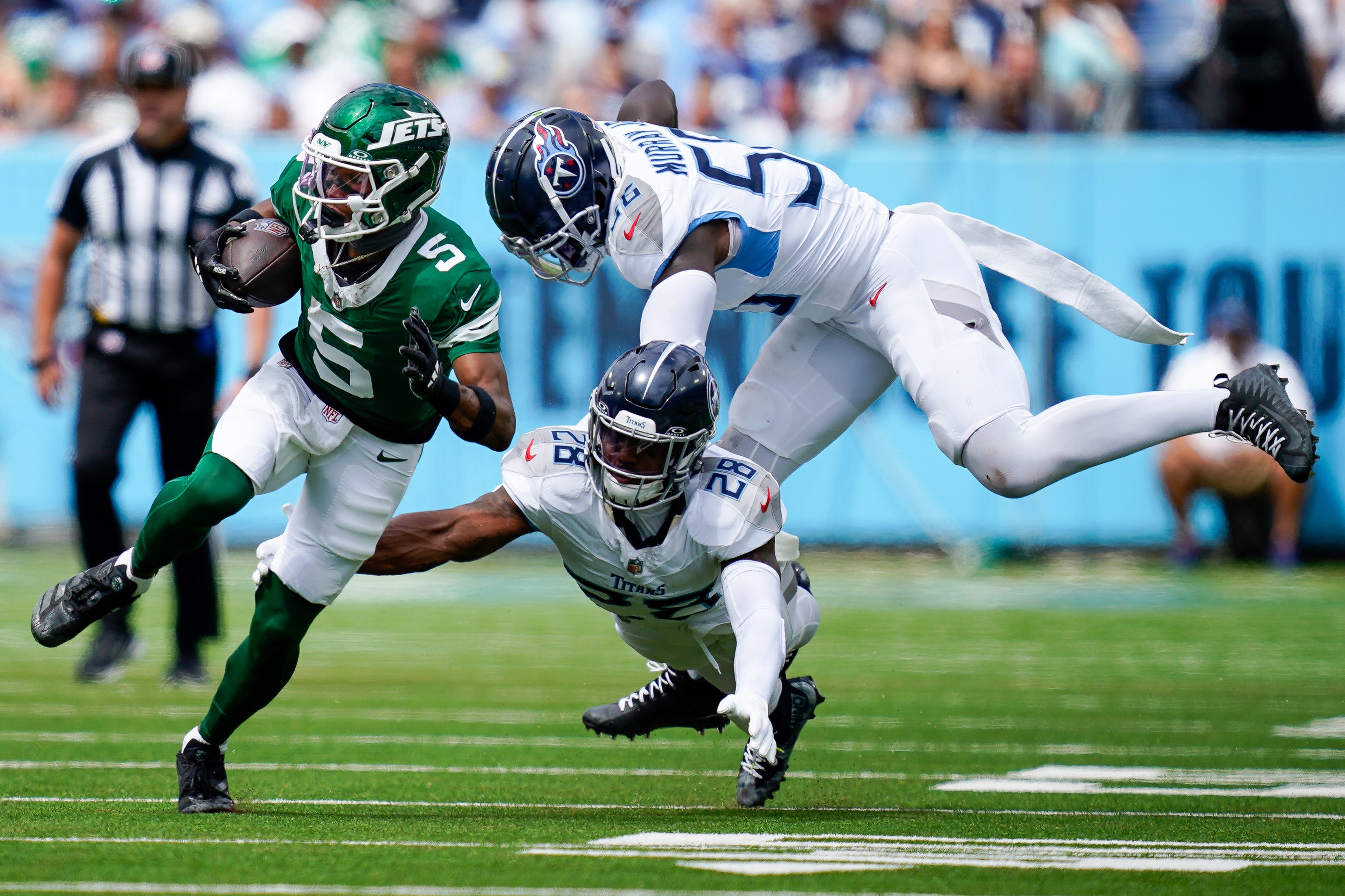 New York Jets wide receiver Garrett Wilson (5) escapes from Tennessee Titans safety Quandre Diggs (28) and linebacker Kenneth Murray Jr. (56) during the second quarter at Nissan Stadium in Nashville, Tenn., Sunday, Sept. 15, 2024.