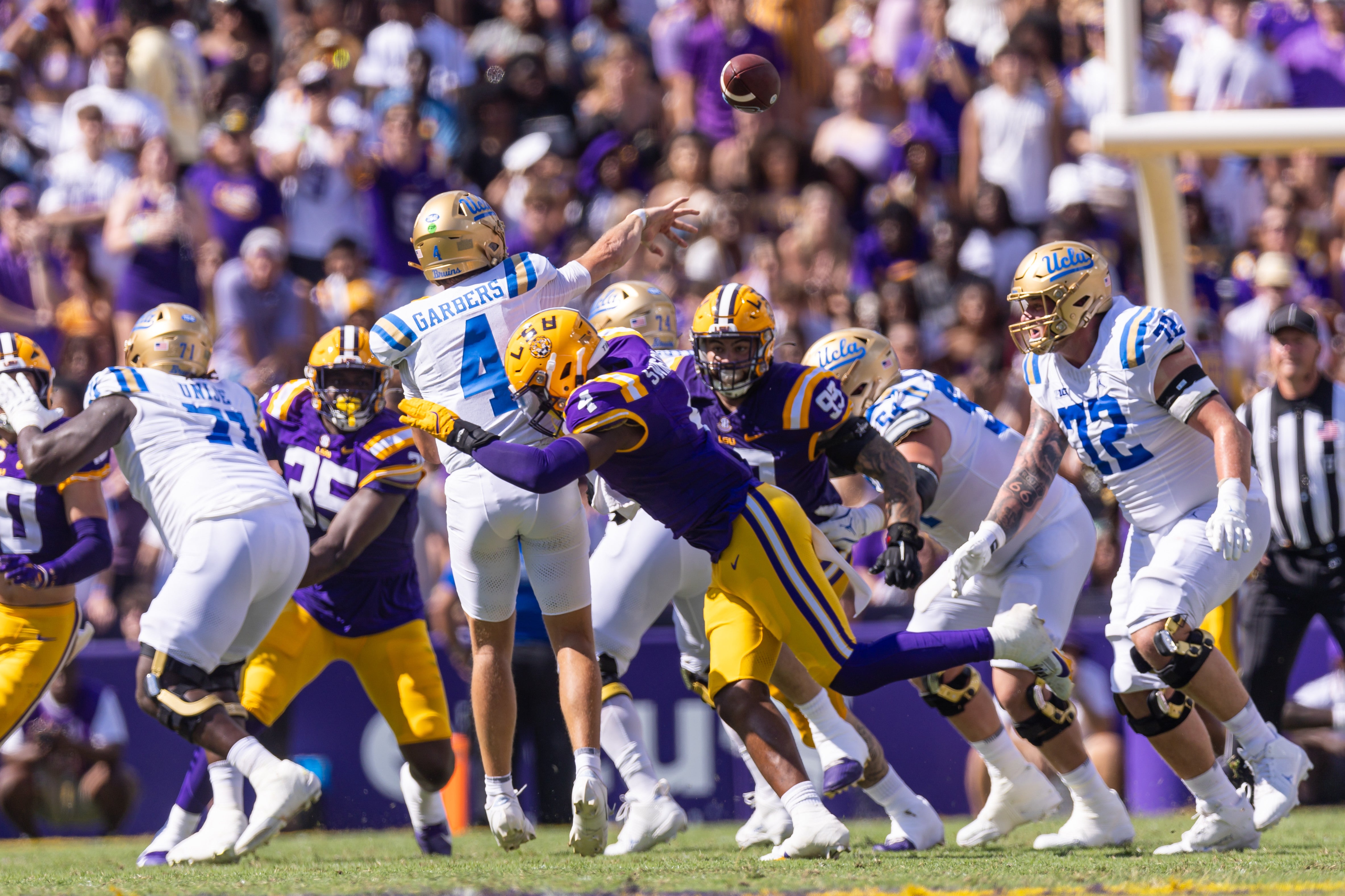 Sep 21, 2024; Baton Rouge, Louisiana, USA; UCLA Bruins quarterback Ethan Garbers (4) releases the ball before being hit by LSU Tigers defensive end Bradyn Swinson (4) during the first half at Tiger Stadium.