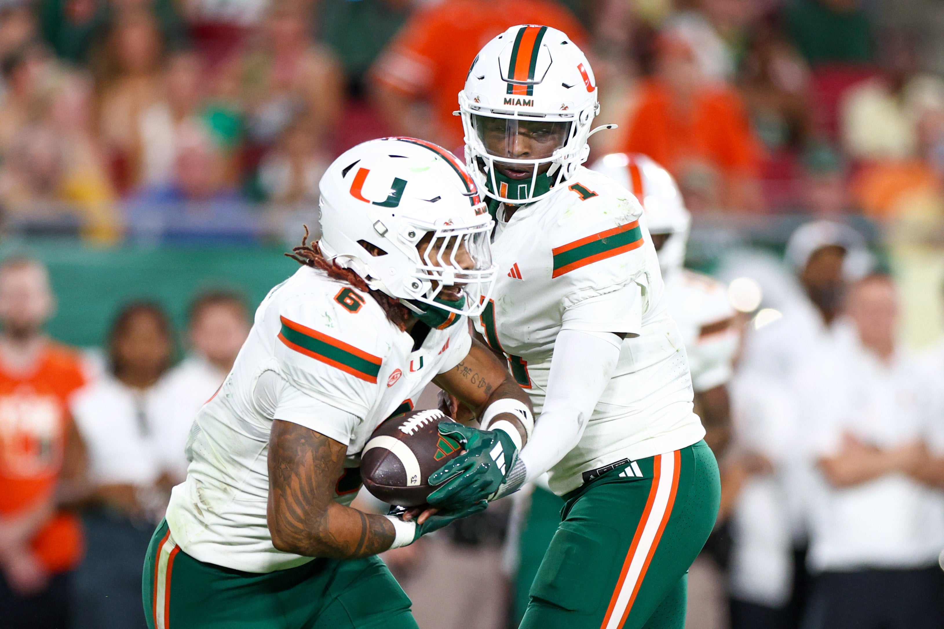 Sep 21, 2024; Tampa, Florida, USA; Miami Hurricanes quarterback Cam Ward (1) hands off to running back Damien Martinez (6) against the South Florida Bulls in the second quarter at Raymond James Stadium.