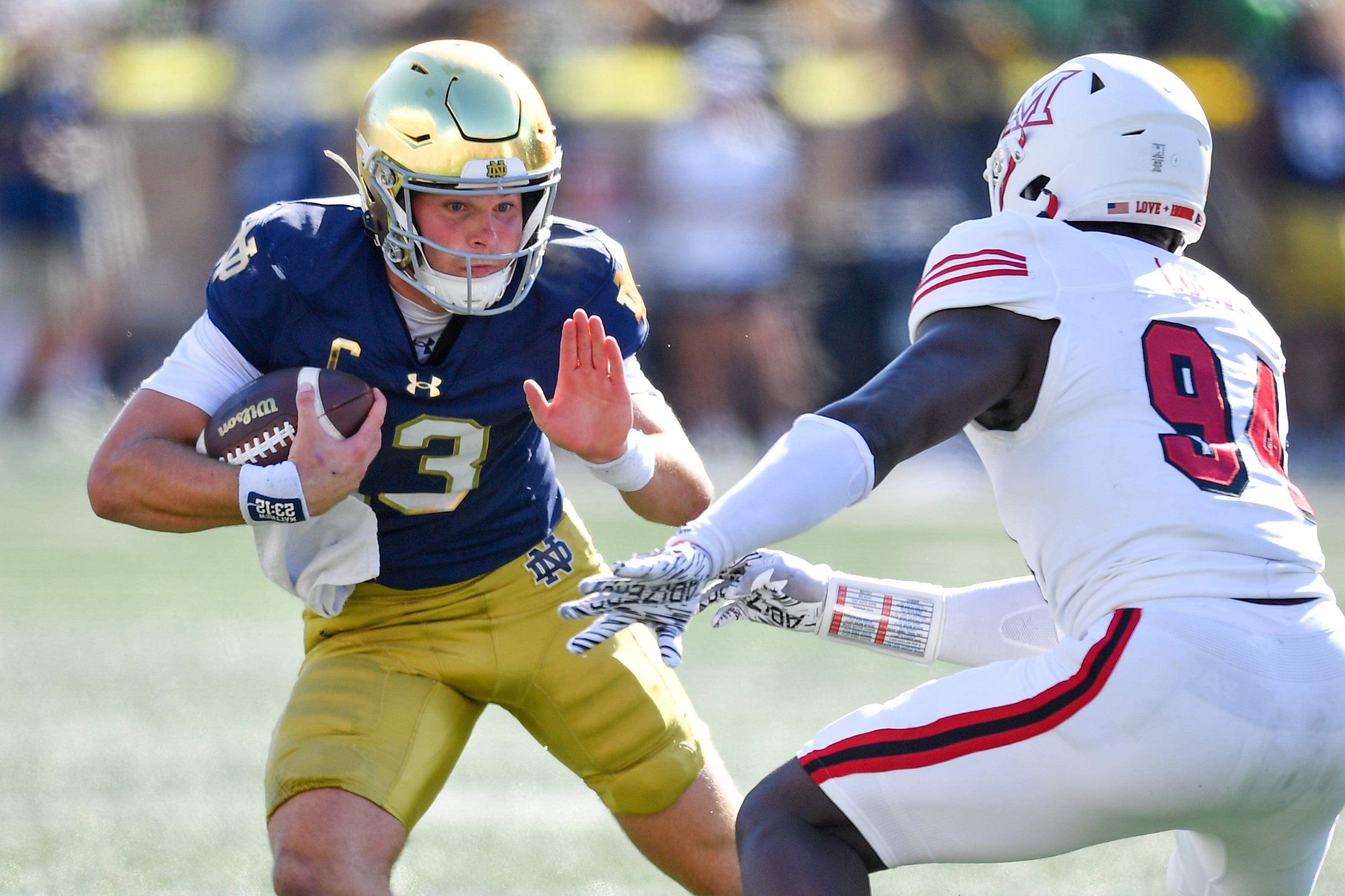 Notre Dame Fighting Irish quarterback Riley Leonard (13) runs the ball as Miami Redhawks defensive end Josh Lukusa (94) defends in the second quarter at Notre Dame Stadium.