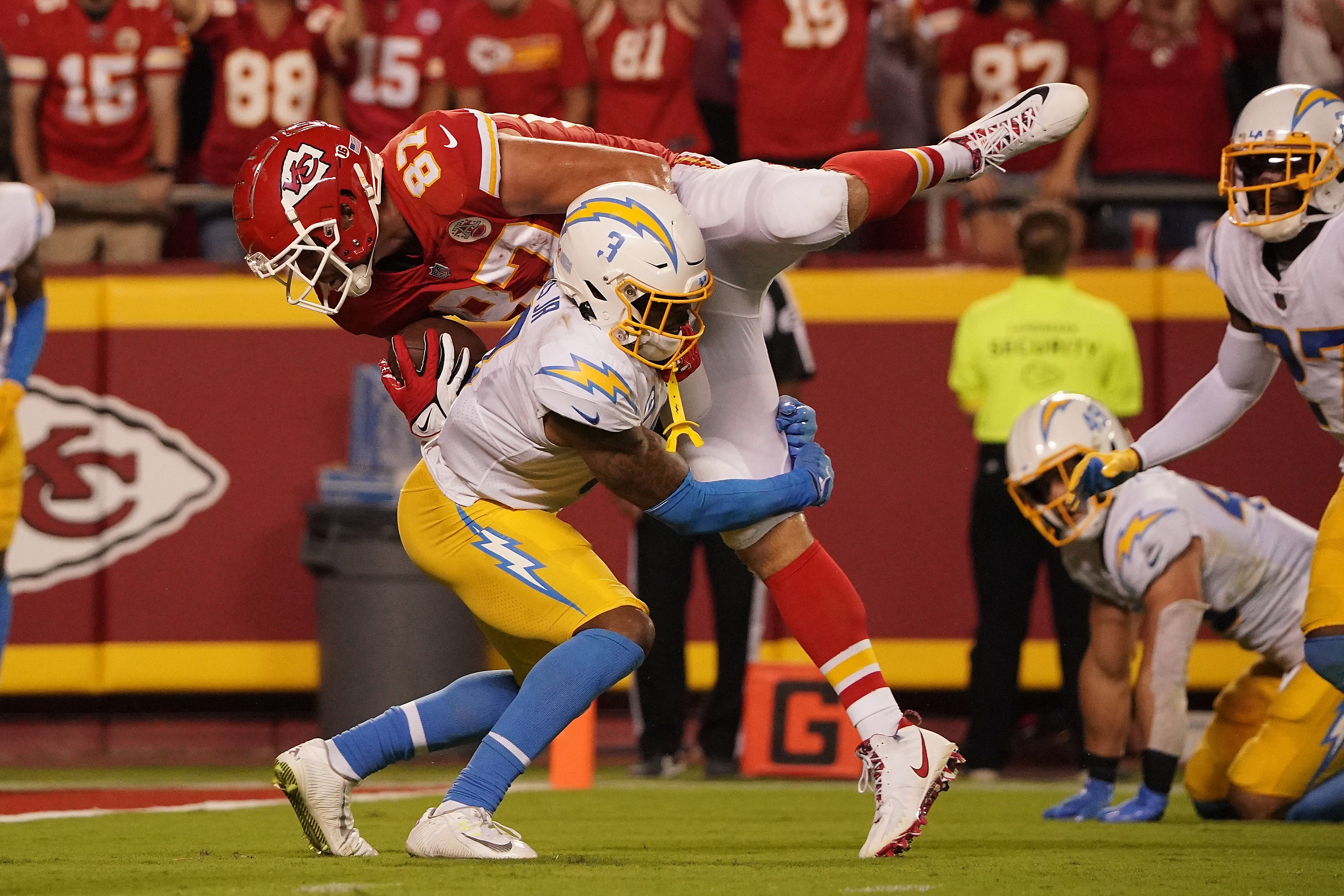 Sep 15, 2022; Kansas City, Missouri, USA; Kansas City Chiefs tight end Travis Kelce (87) is brought down by Los Angeles Chargers safety Derwin James Jr. (3) during the second half at GEHA Field at Arrowhead Stadium.
