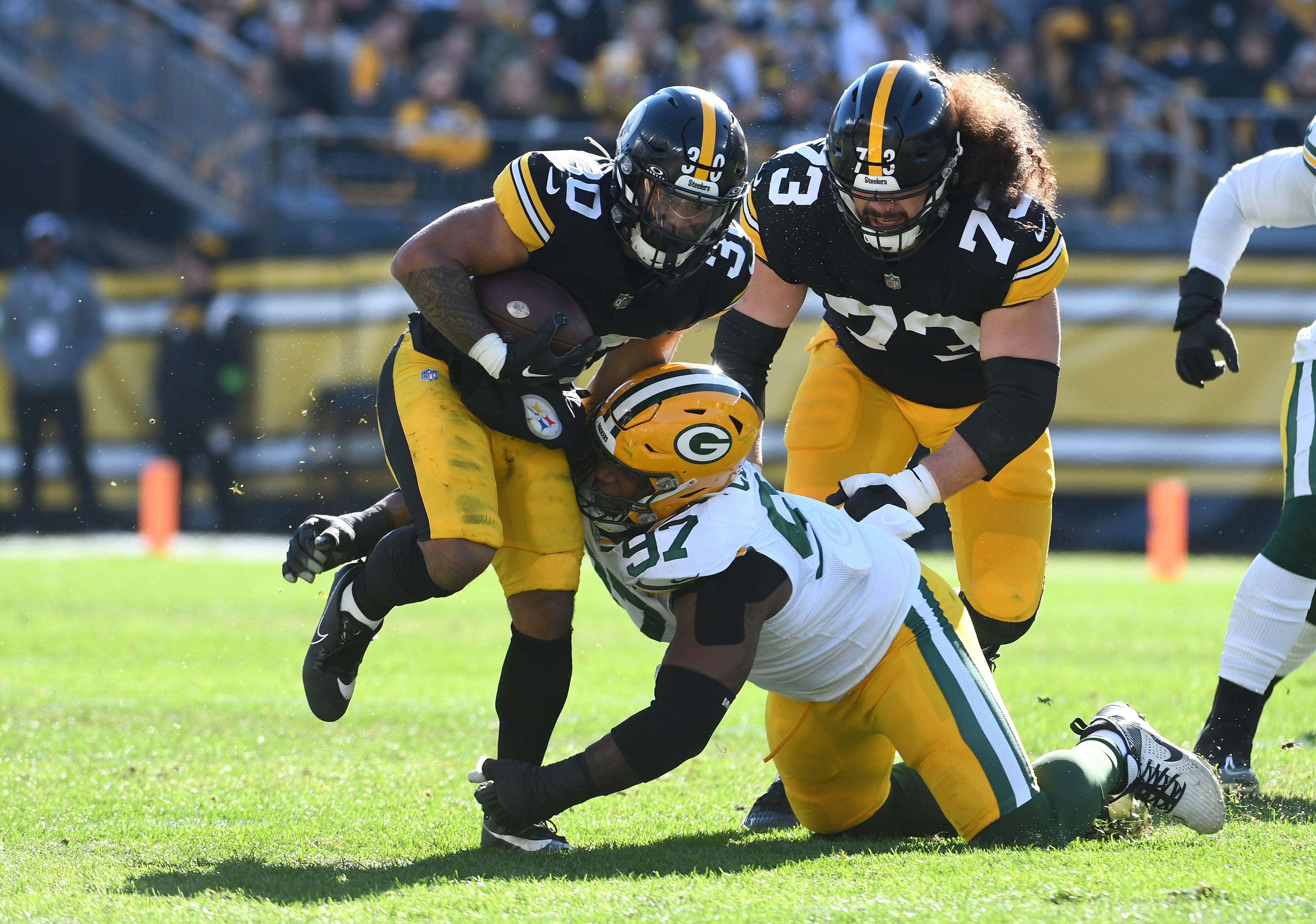 Nov 12, 2023; Pittsburgh, Pennsylvania, USA; Pittsburgh Steelers running back Jaylen Warren (30) and Green Bay Packers defensive lineman Kenny Clark (97) as offensive lineman Isaac Seumalo (73) follows the play during the first quarter at Acrisure Stadium. Mandatory Credit: Philip G. Pavely-Imagn Images