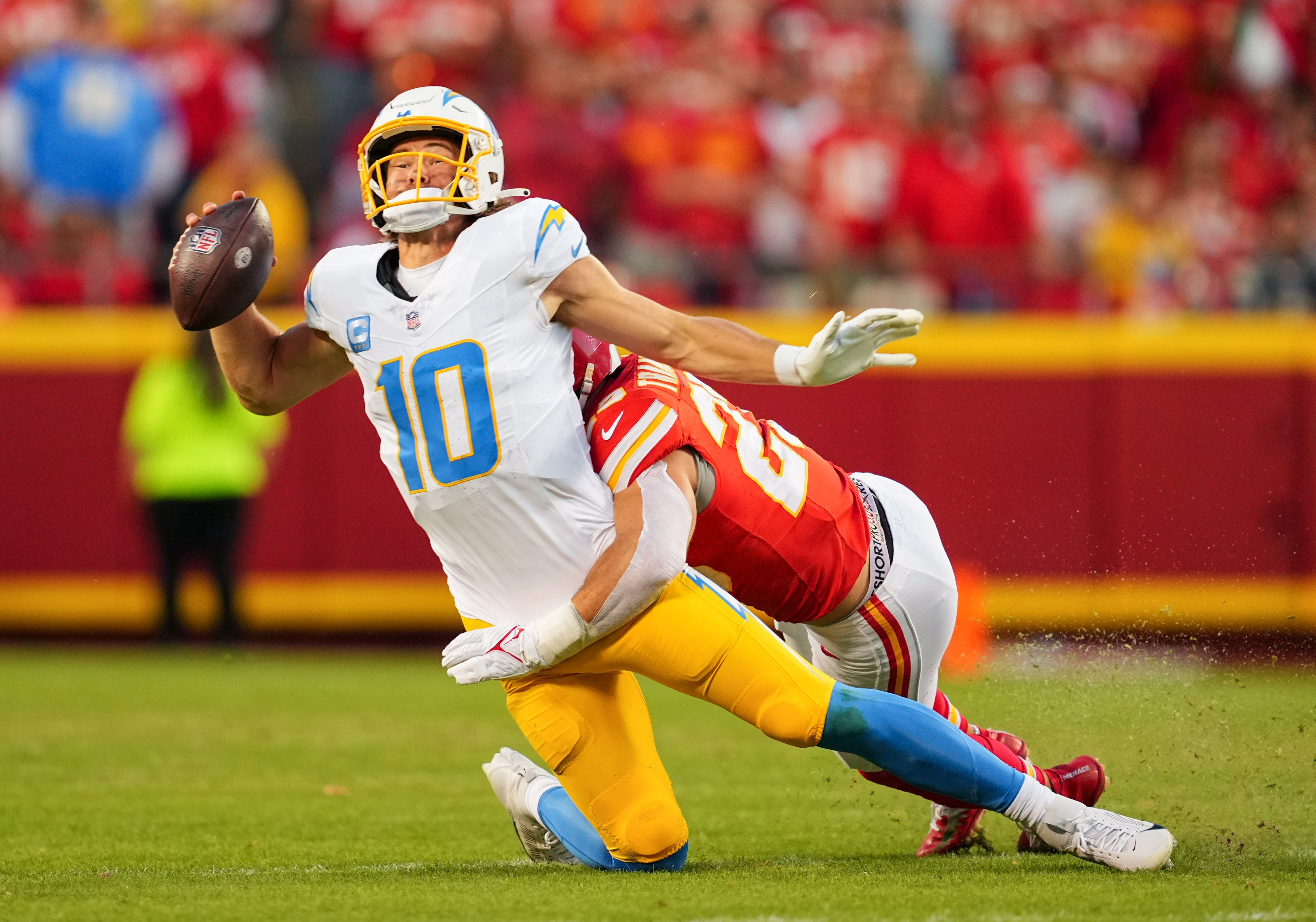 Oct 22, 2023; Kansas City, Missouri, USA; Los Angeles Chargers quarterback Justin Herbert (10) is tackled by Kansas City Chiefs linebacker Drue Tranquill (23) during the second half at GEHA Field at Arrowhead Stadium.