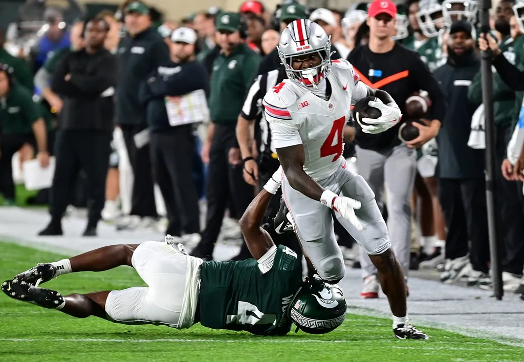 Ohio State Buckeyes wide receiver Jeremiah Smith (4) runs past Michigan State Spartans defensive back Ed Woods (4) in the first quarter at Spartan Stadium.
