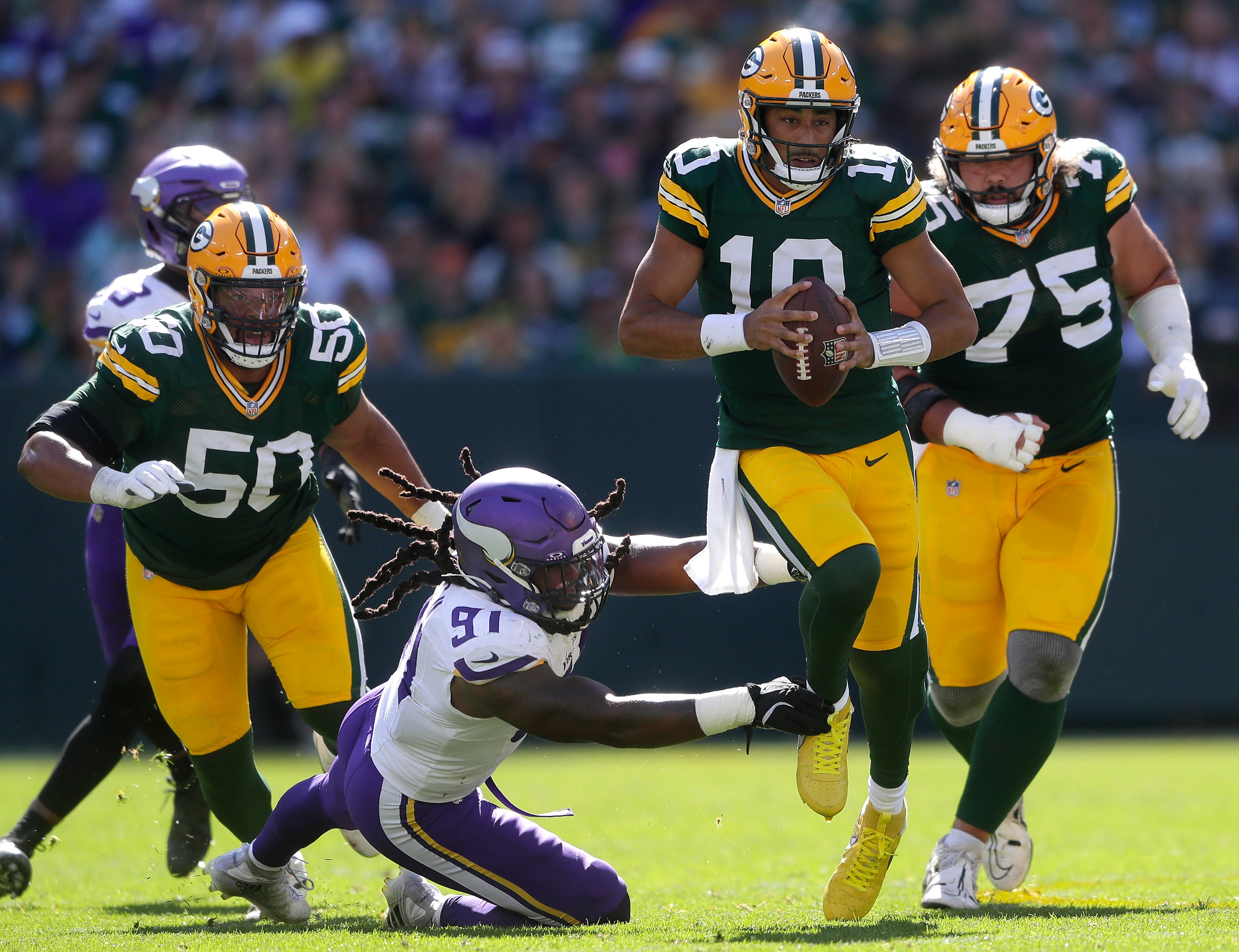 Green Bay Packers quarterback Jordan Love (10) is chased by Minnesota Vikings linebacker Pat Jones II (91) at Lambeau Field.