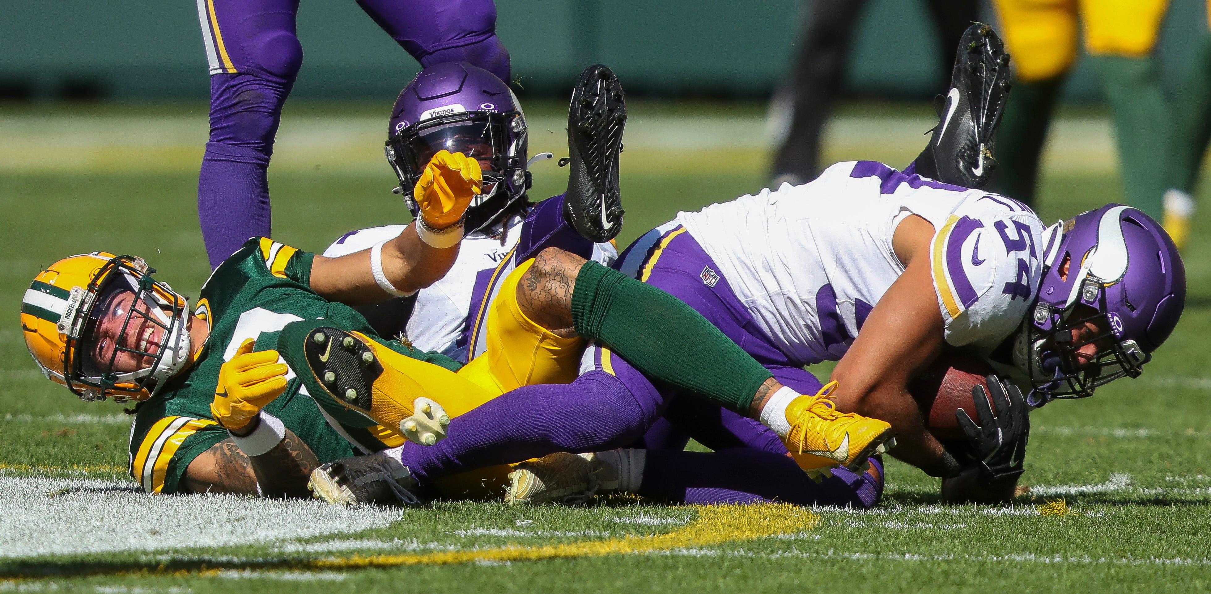 Green Bay Packers wide receiver Christian Watson (9) winces in pain as Minnesota Vikings linebacker Kamu Grugier-Hill (54) comes away with an interception on Sunday, September 29, 2024, at Lambeau Field in Green Bay, Wis. Watson injured his ankle on the play as the Vikings won the game, 31-29.
