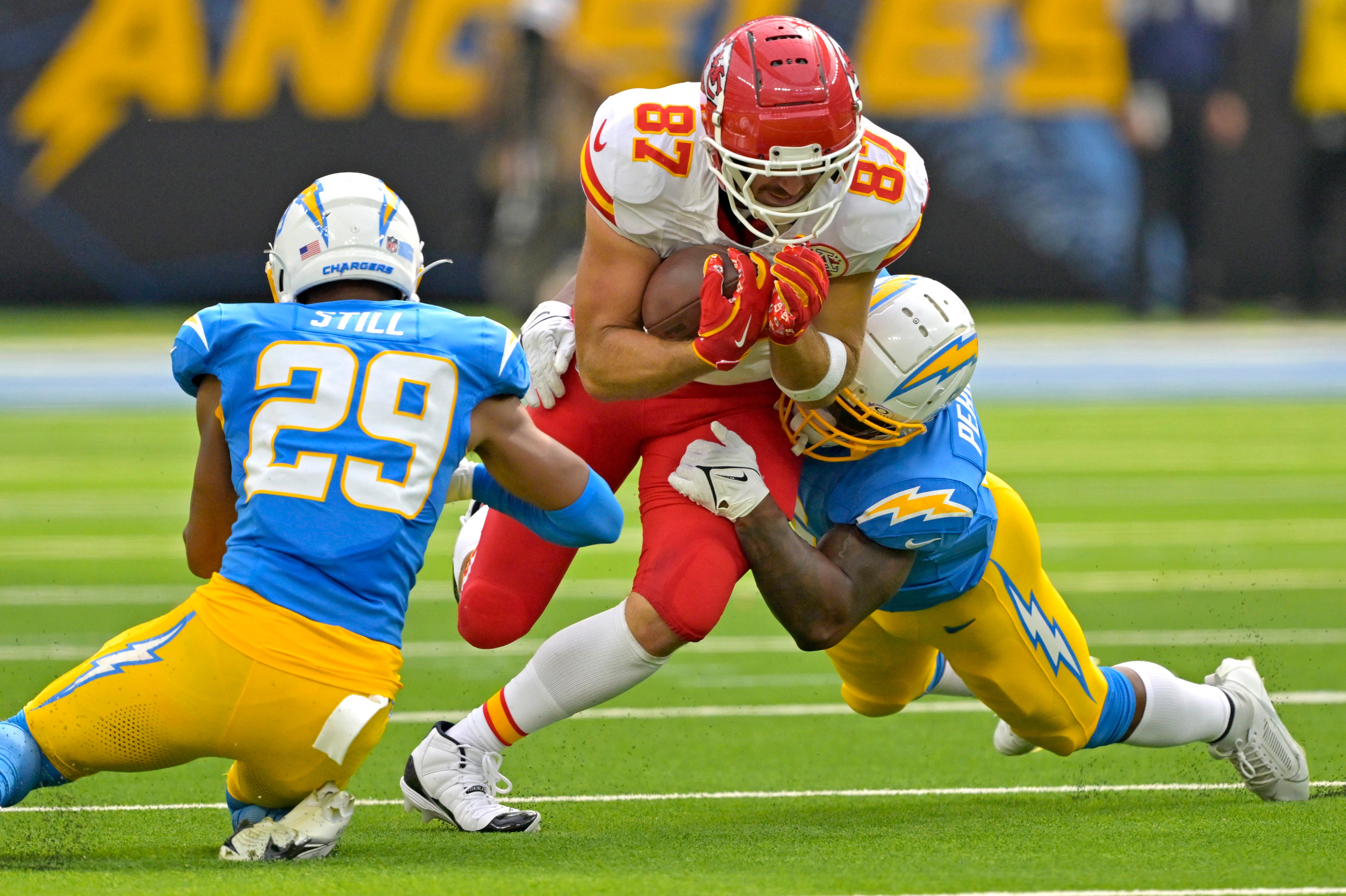 Sep 29, 2024; Inglewood, California, USA; Kansas City Chiefs tight end Travis Kelce (87) is stopped by Los Angeles Chargers defensive tackle CJ Okoye (69) an cornerback Tarheeb Still (29) after a complete pass in the first half at SoFi Stadium.