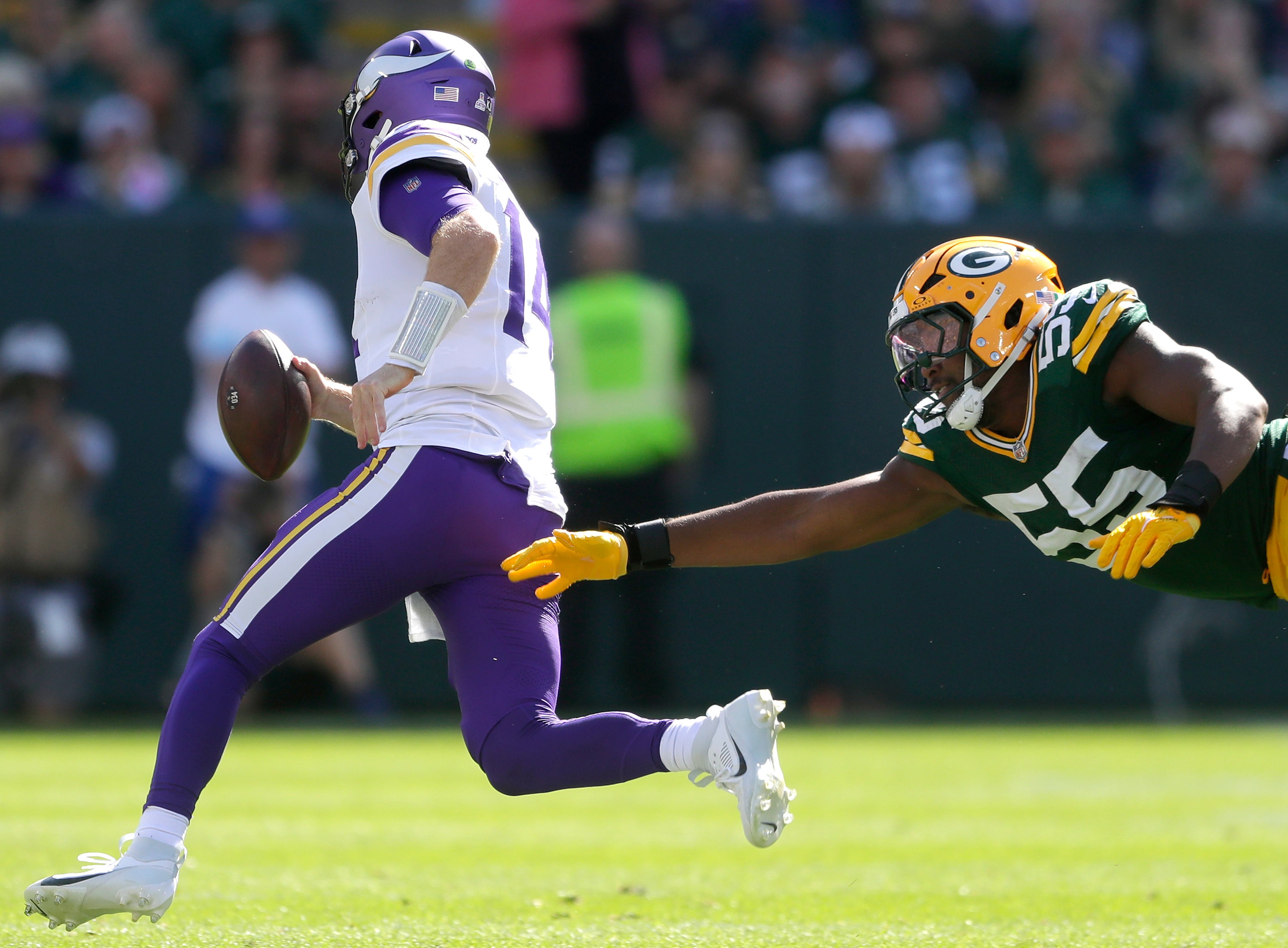 Sep 29, 2024; Green Bay, Wisconsin, USA; Green Bay Packers defensive end Kingsley Enagbare (55) chases Minnesota Vikings quarterback Sam Darnold (14) during their football game on Sunday, September 29, 2024 at Lambeau Field in Green Bay, Wis. The Vikings defeated the Packers 31-29.